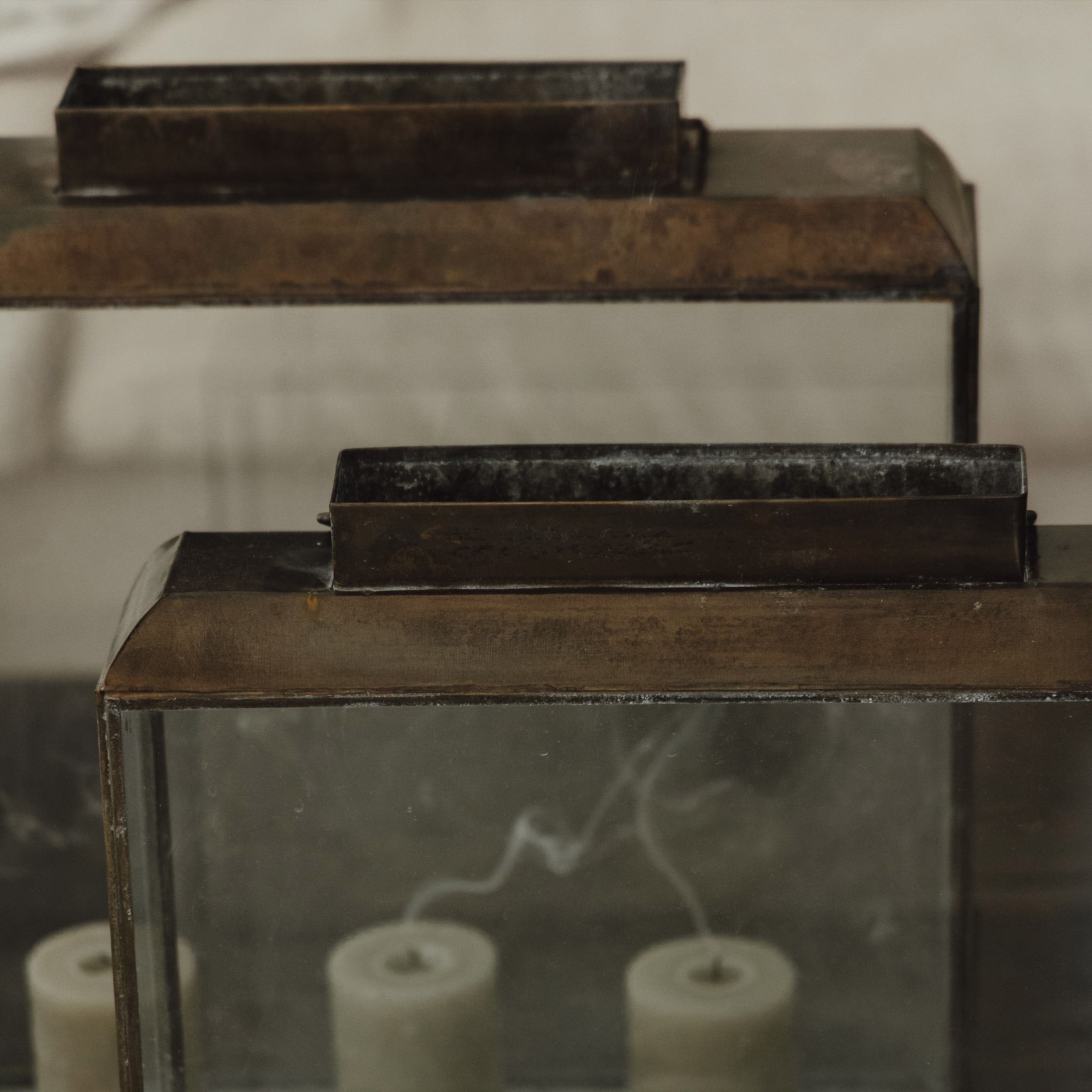 Lanterne en métal vieilli avec vitre et trois bougies blanches éteintes à l'intérieur