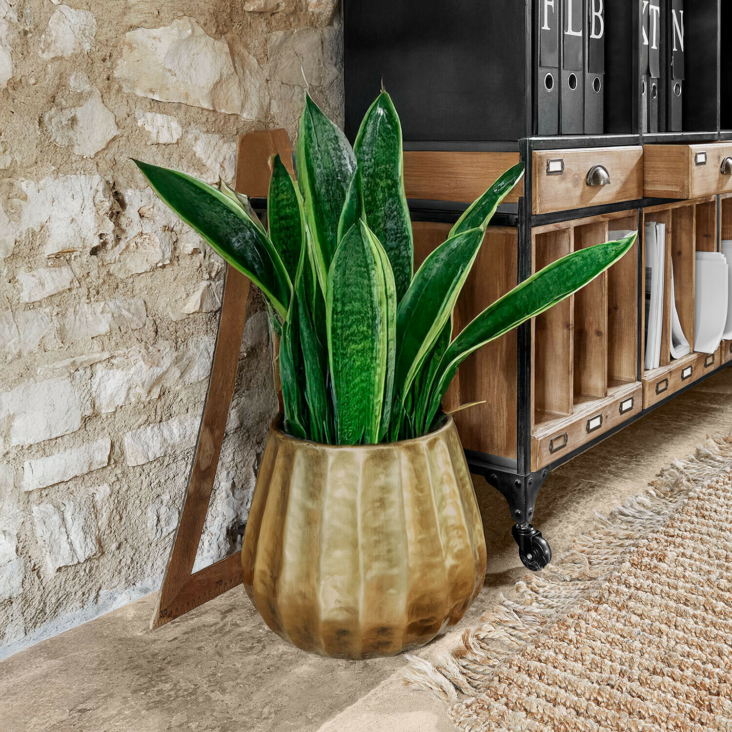 Plante en pot dans un cache-pot en céramique marron à côté d'une étagère en bois avec éléments métalliques