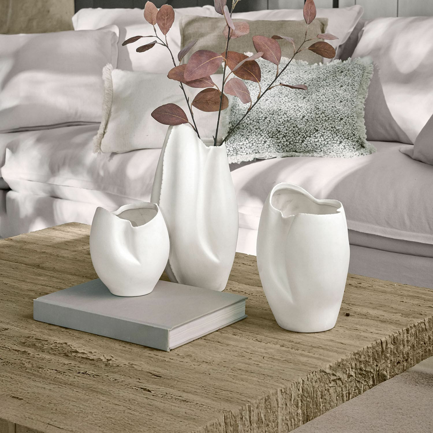 Lot de 3 vases Kazimad Ensemble de trois vases en céramique blanche aux formes irrégulières sur une table en bois dans un salon