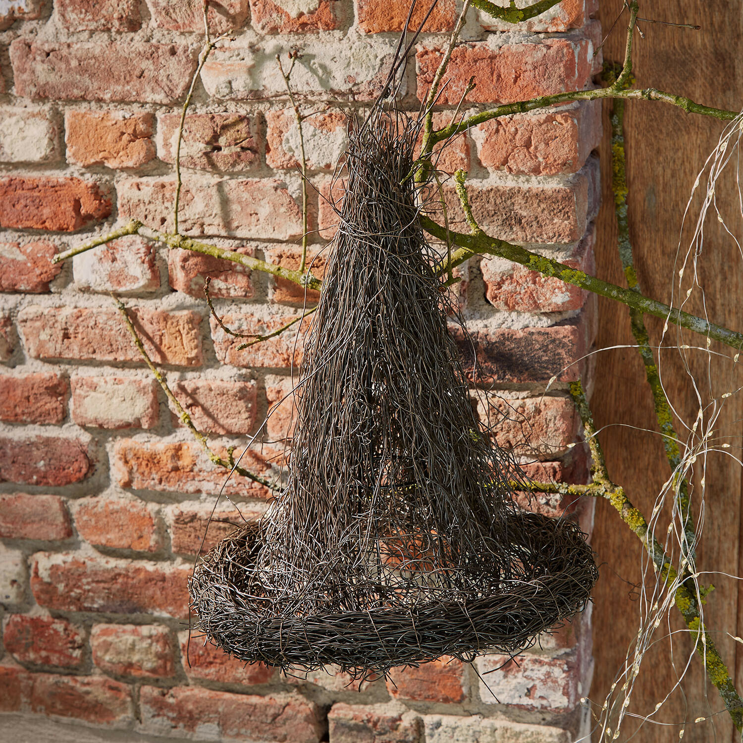 Chapeau décoratif Talmora Décoration suspendue en fil métallique noir en forme de chapeau de sorcière devant un mur en briques