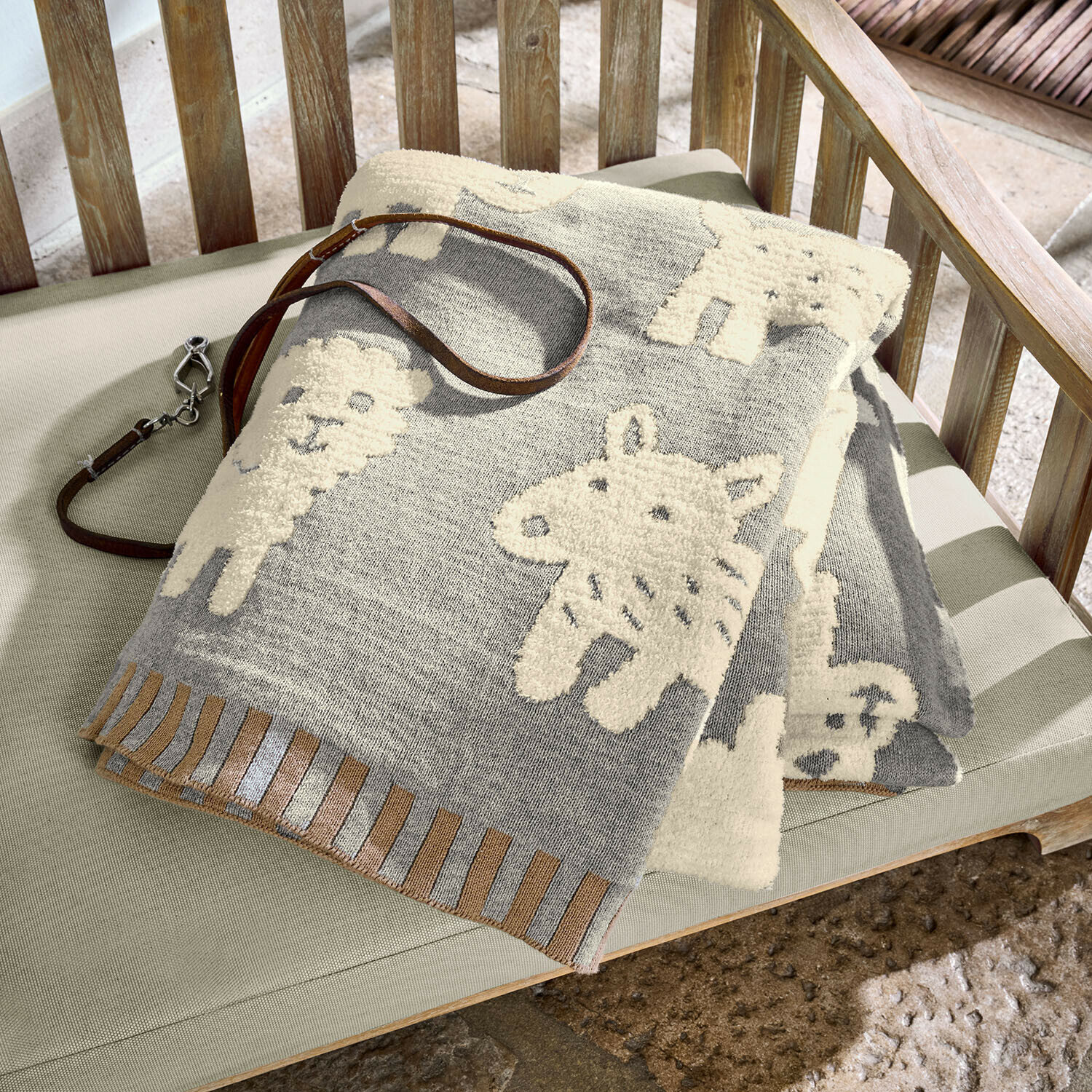 Plaid en coton gris avec motifs d'animaux crème sur banc en bois, couverture décorative douce