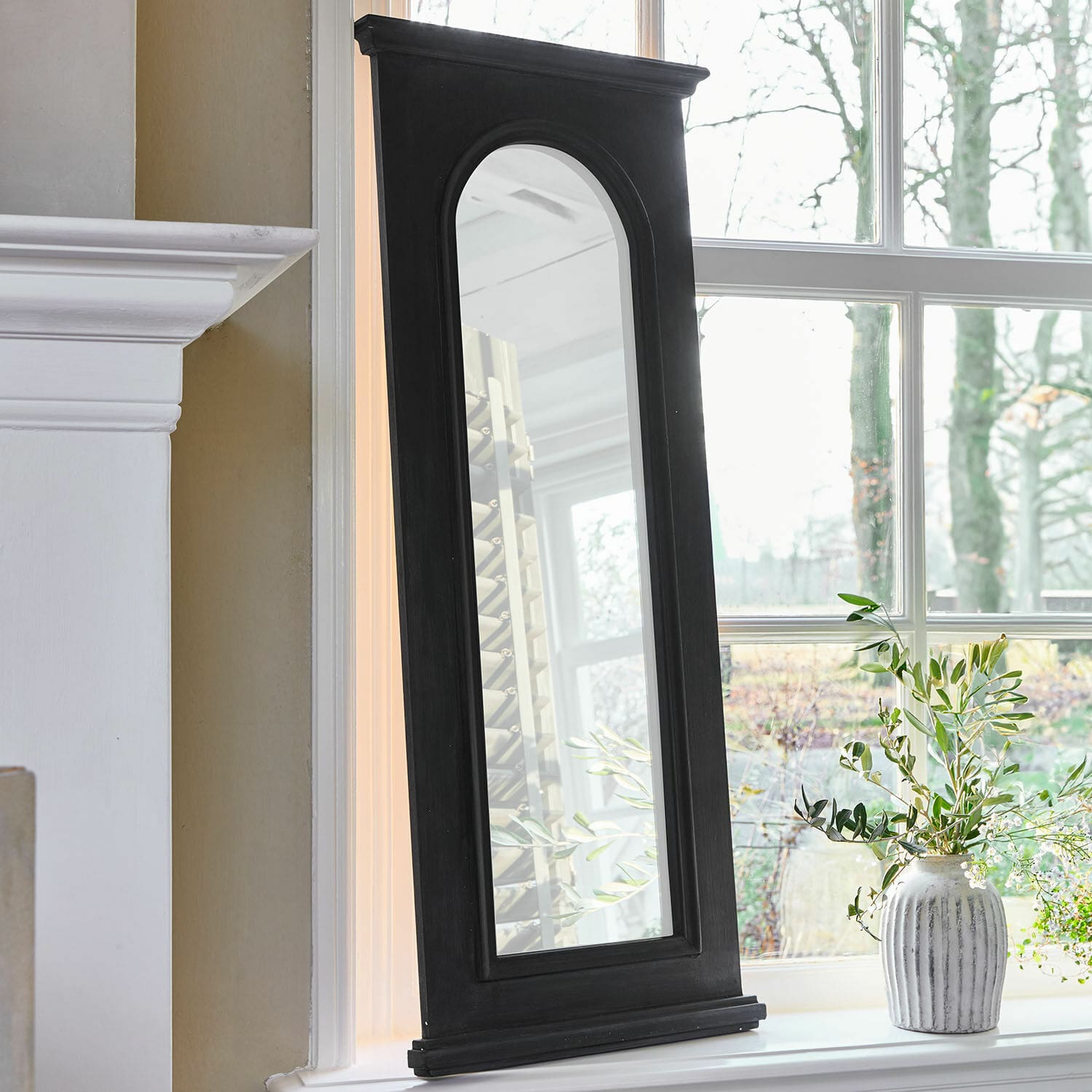 Miroir Timbercrest Miroir avec cadre en bois noir et bord supérieur arrondi posé sur le rebord de fenêtre