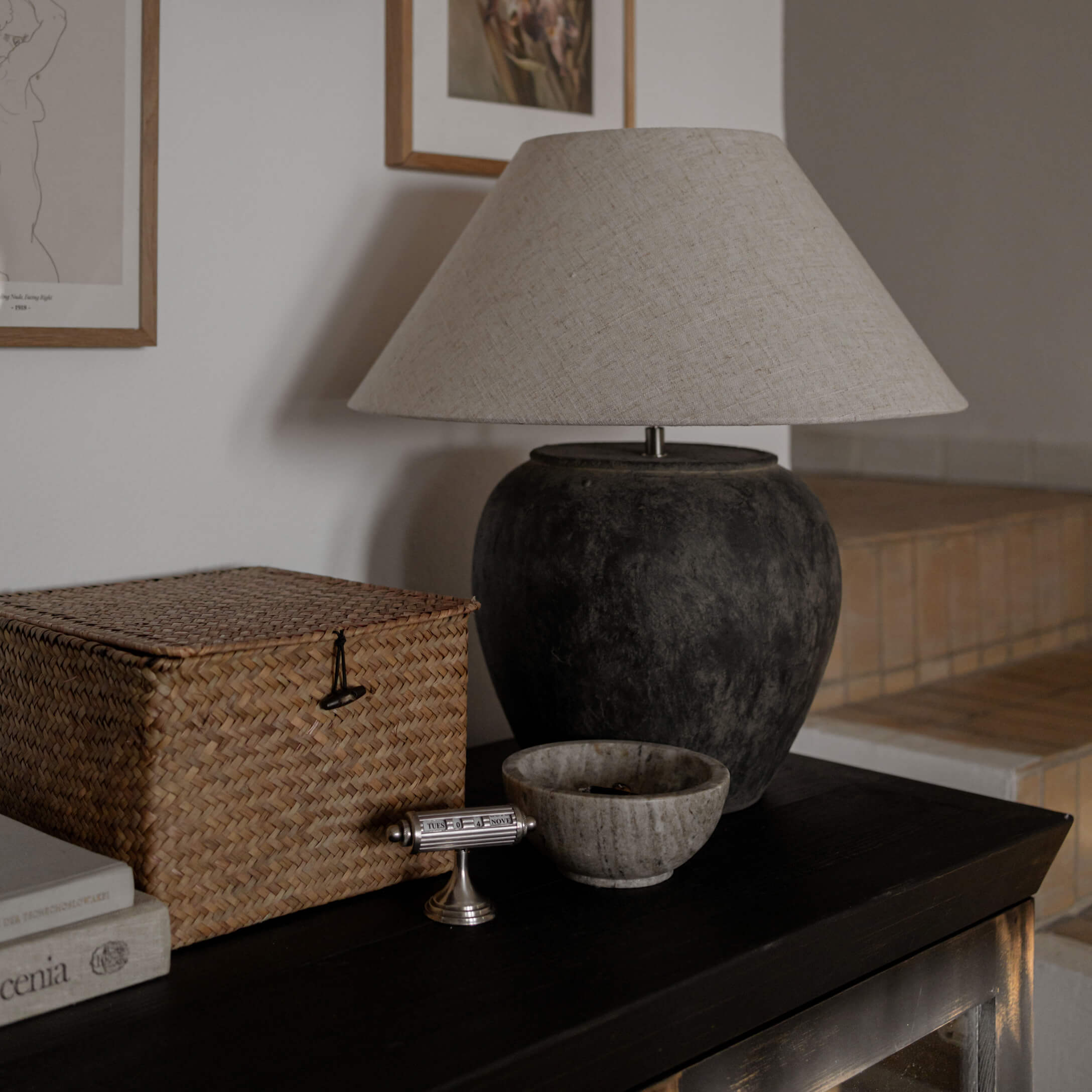 Lampe de table avec base en céramique noire et abat-jour beige sur une table sombre dans un salon