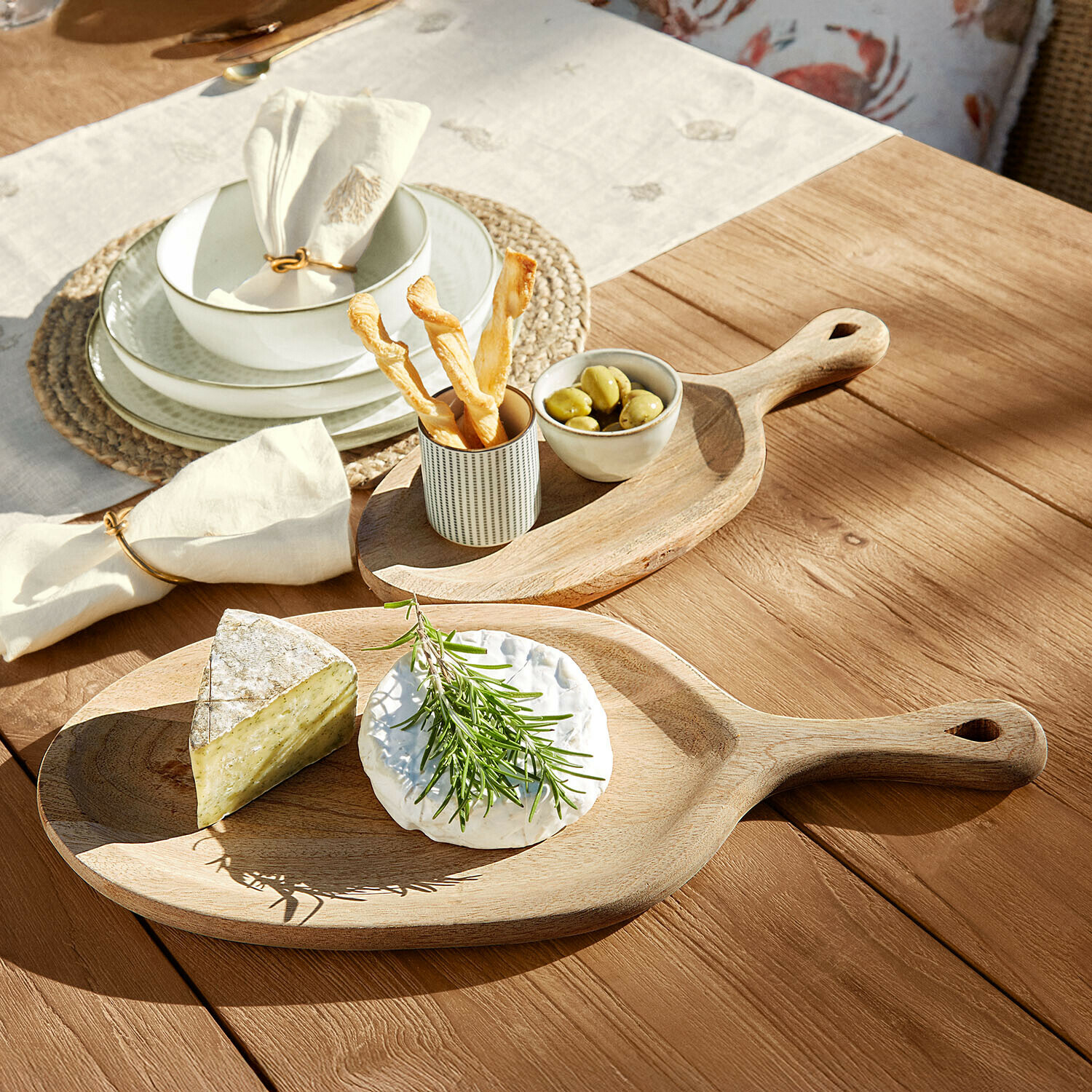 Lot de 2 plateaux Nolaria Planche à découper en bois avec fromages, olives et snacks sur table en bois sous lumière naturelle