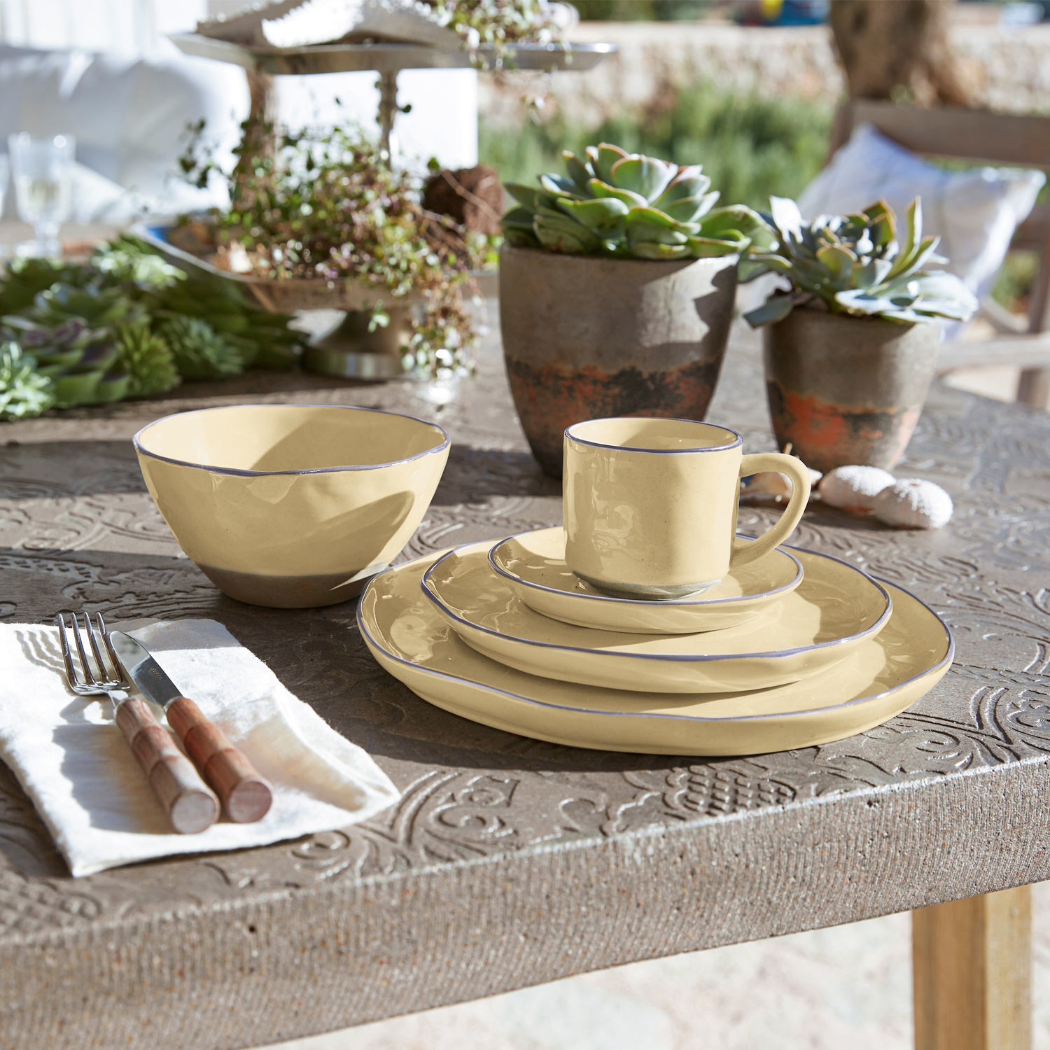 Service 30 pièces Biarré Service de vaisselle en céramique crème avec bord bleu sur une table rustique décorée de plantes succulentes