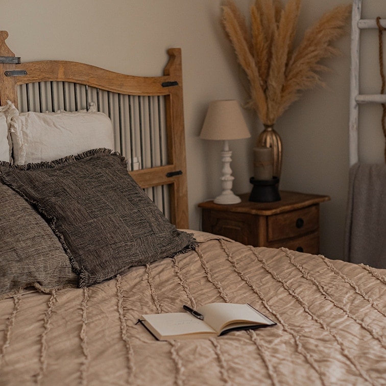 Chambre chaleureuse avec lit en bois et couette beige, décorations bohèmes naturelles