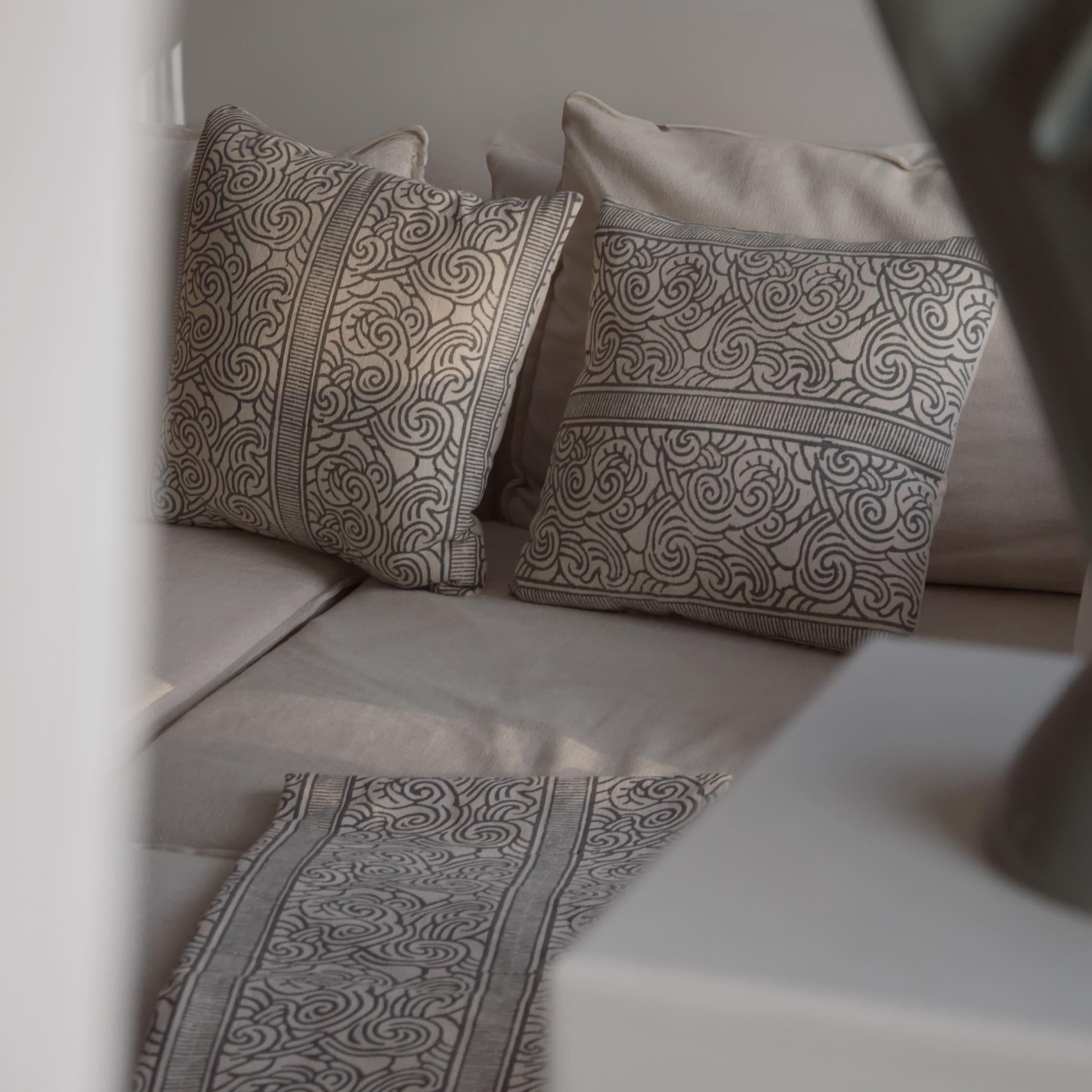 Coussins et chemin de table beige avec motif noir sur tissu clair, décoration intérieure salon