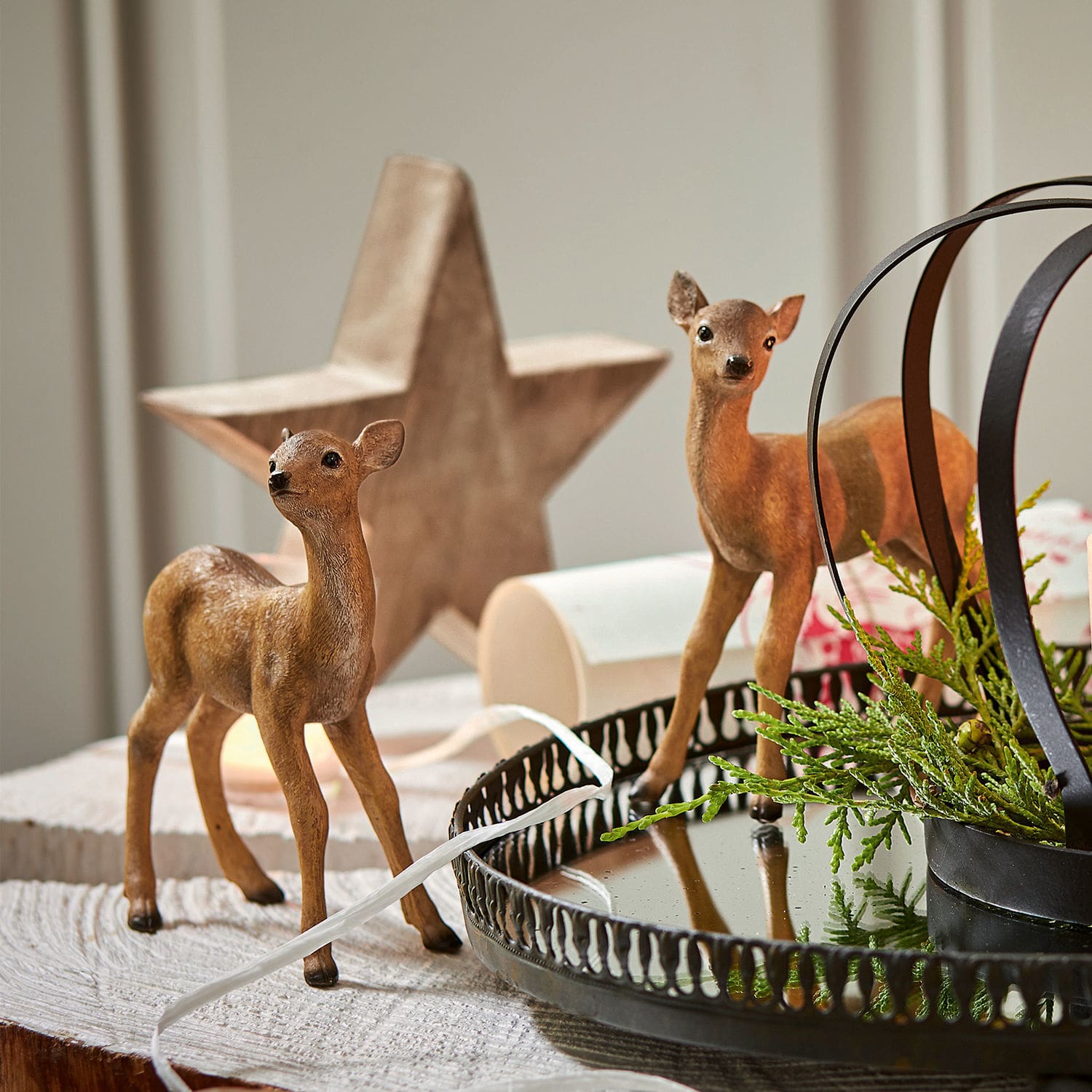 Lot de 2 faons Plantis Deux figurines de faons marron sur une table en bois avec un plateau en métal et des branches vertes décoratives