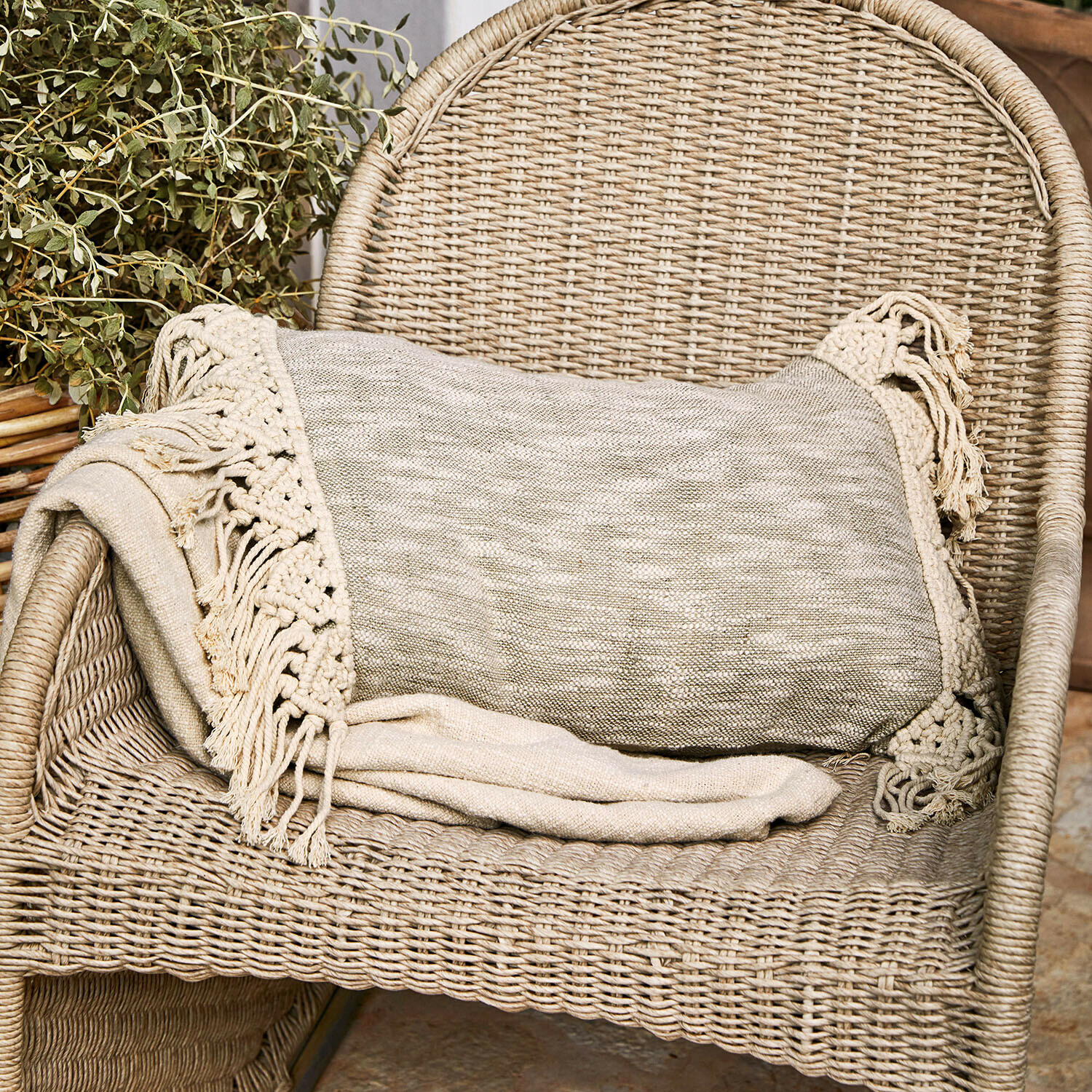 Plaid beige avec franges sur fauteuil en osier, décoration intérieure chaleureuse et confortable