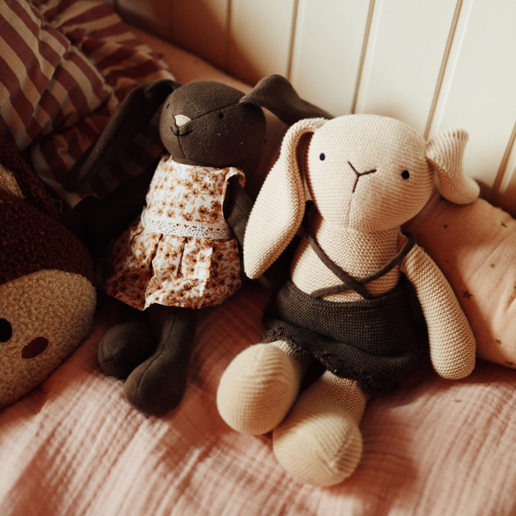 Deux peluches lapins en tissu avec robes, jouets doux pour chambre d'enfant sur lit rose