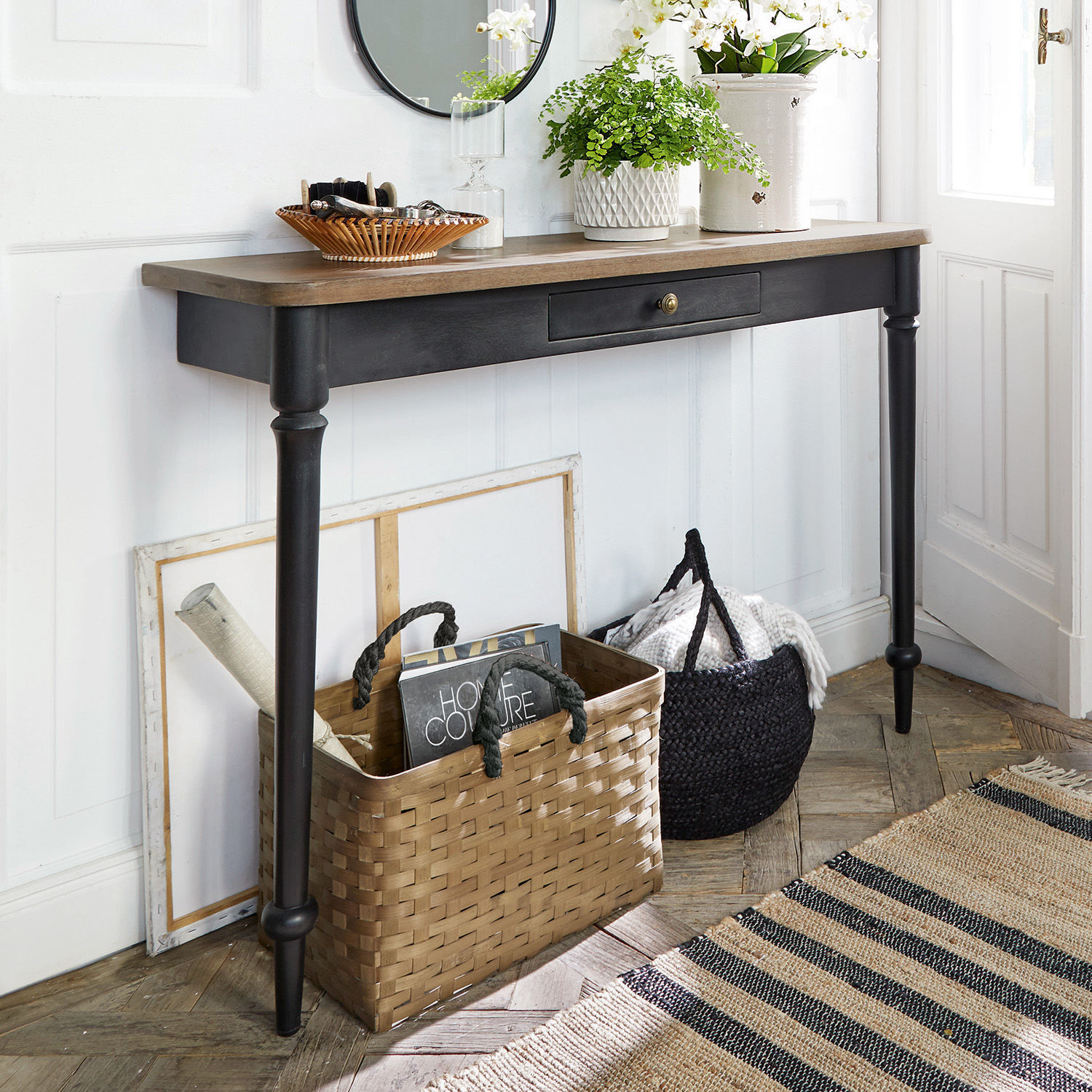 Console Jarobrod Console noire avec plateau en bois dans un intérieur clair avec paniers de rangement en osier