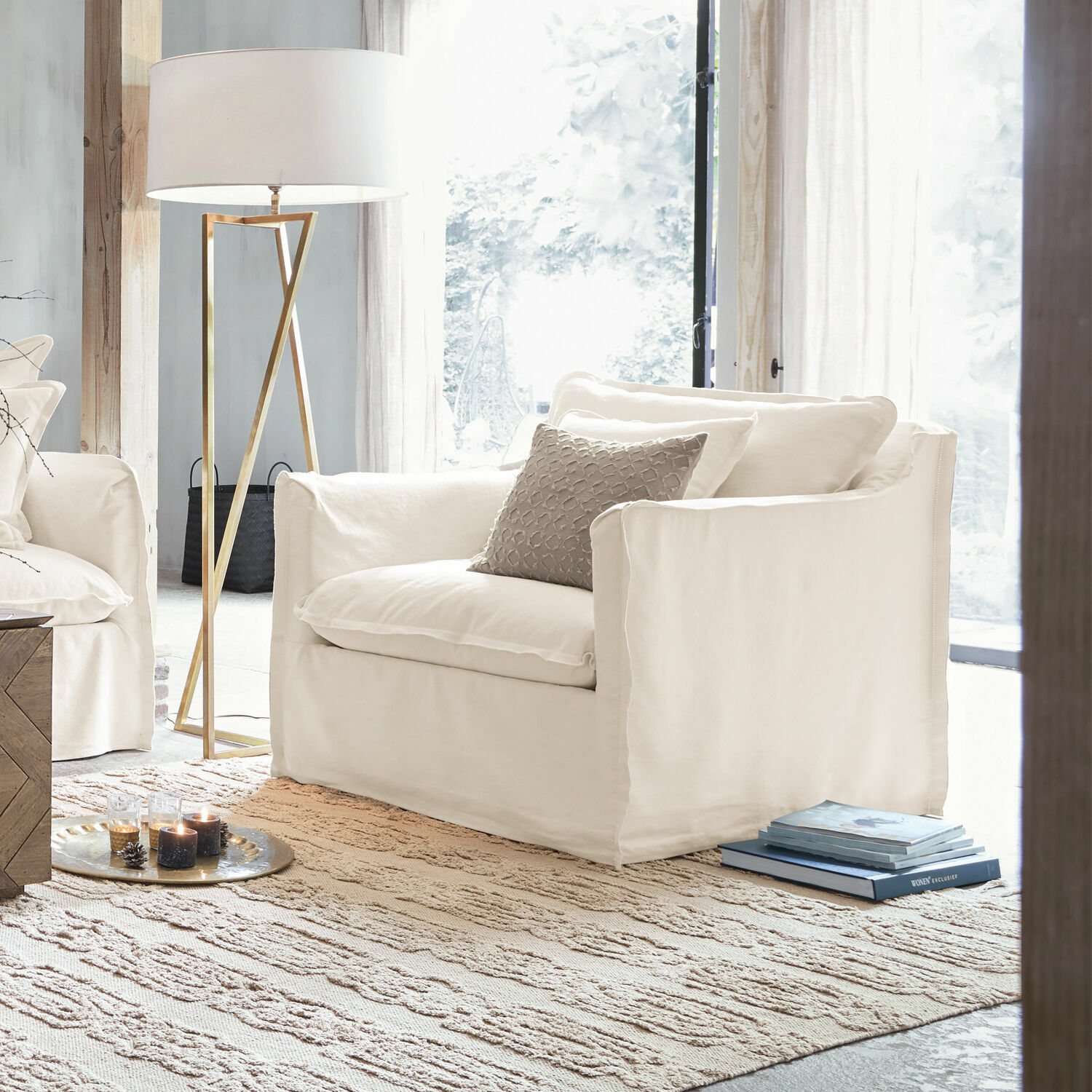 Fauteuil Tienen Fauteuil blanc en tissu dans un salon lumineux avec lampe sur pied et tapis, design moderne.