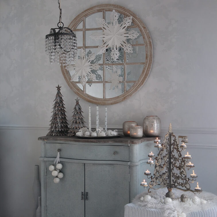 Commode grise avec décorations de Noël, sapins en métal et chandelier vintage avec bougies allumées