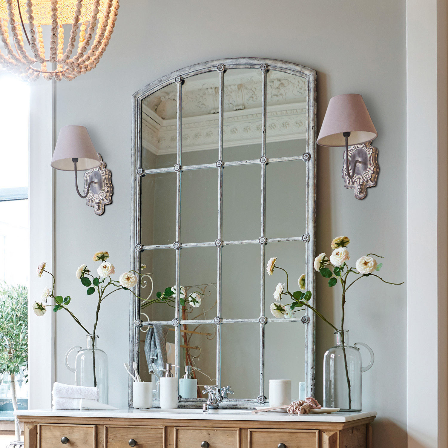 Miroir Tobiah Grand miroir à cadre métallique vintage au-dessus d'une commode en bois avec fleurs et appliques murales