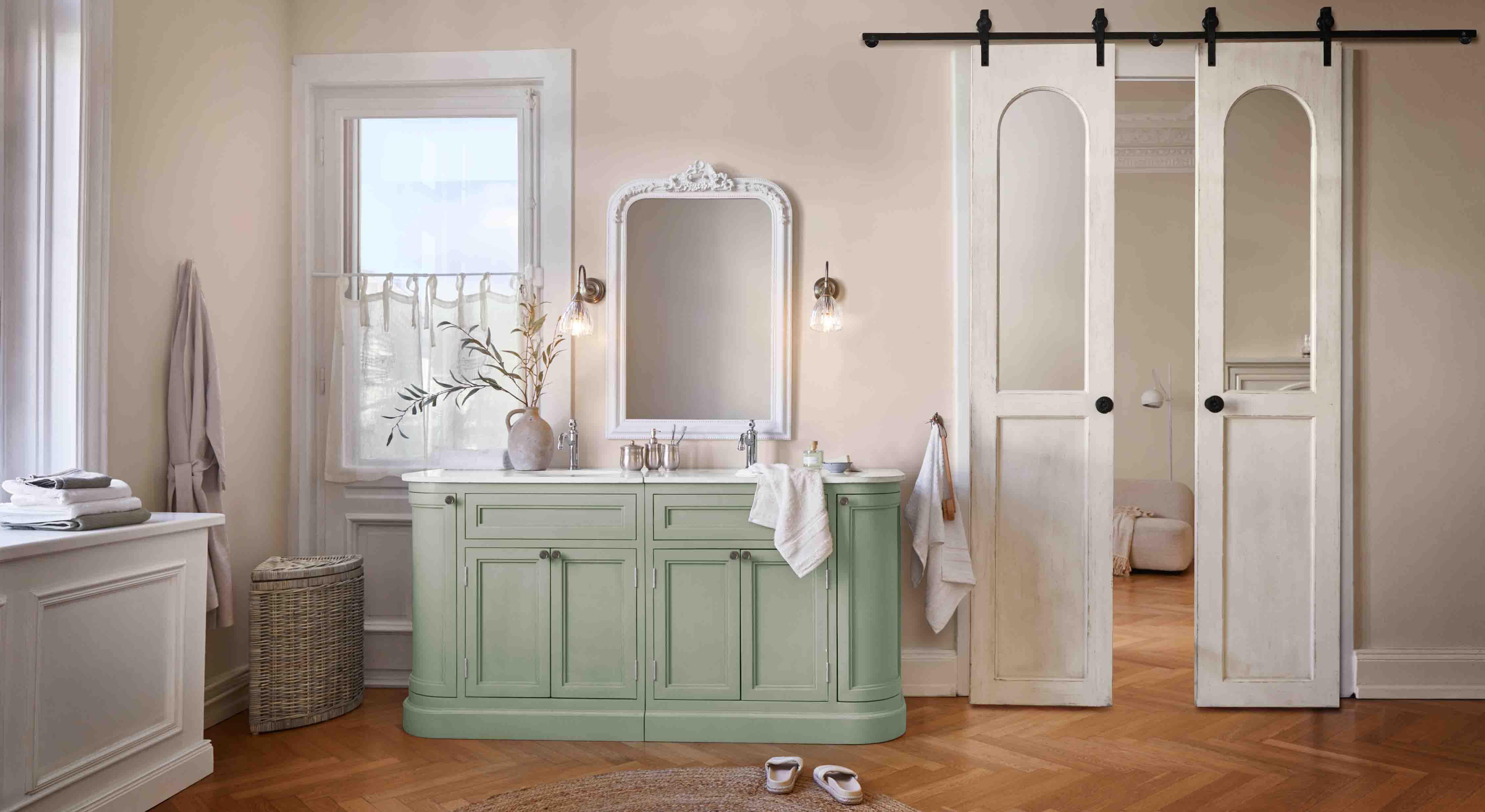 Meuble de salle de bain vert pastel avec plan en marbre blanc et miroir vintage décoratif