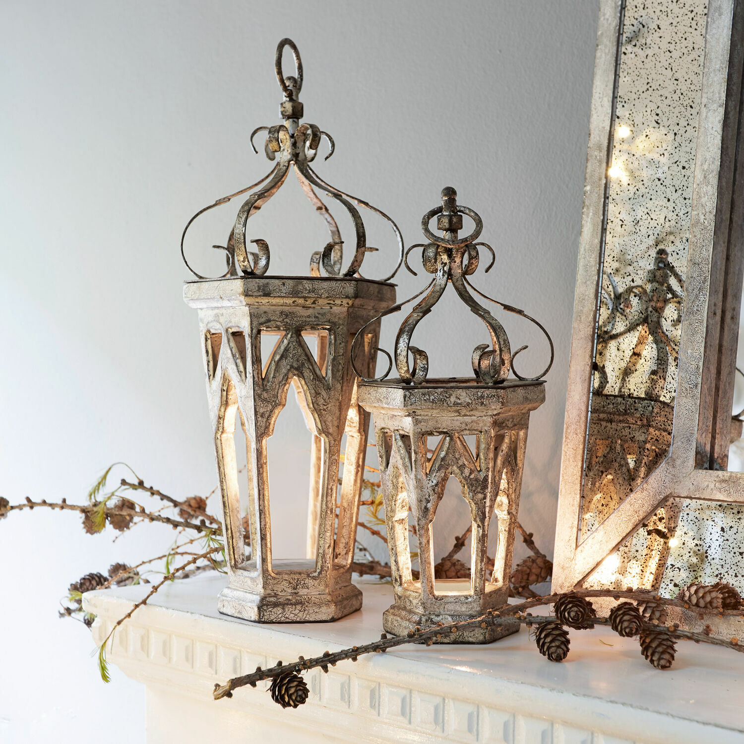 Lot de 2 décorations Morvant Lanterne décorative en métal argenté vieilli style vintage posée sur une cheminée avec pommes de pin