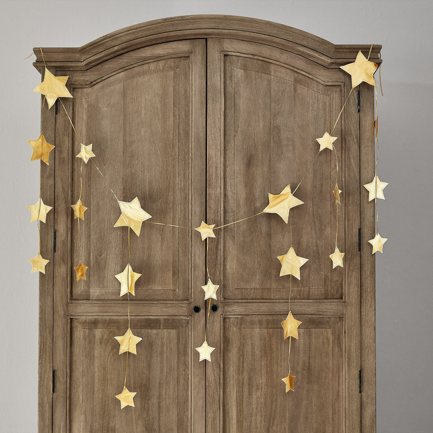 Guirlande Étoilin Guirlande d'étoiles dorées suspendue sur une armoire en bois, décoration intérieure festive