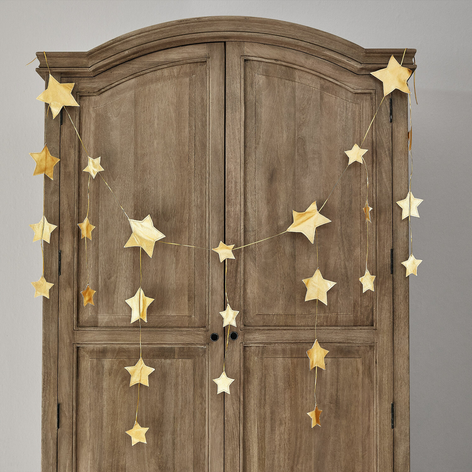Guirlande Étoilin Guirlande d'étoiles dorées suspendue sur une armoire en bois, décoration intérieure festive