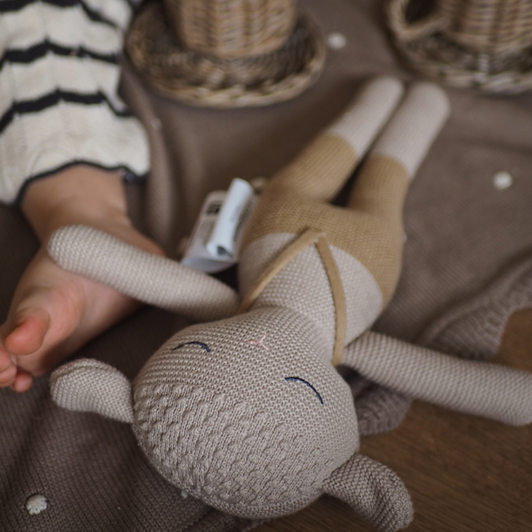 Jouet en tricot doux en forme d'animal beige et marron clair sur fond marron
