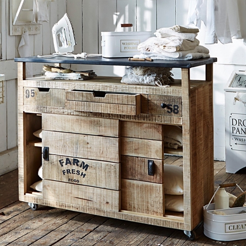 Meuble en bois rustique sur roulettes avec plateau et tiroirs, idéal pour rangement dans la buanderie