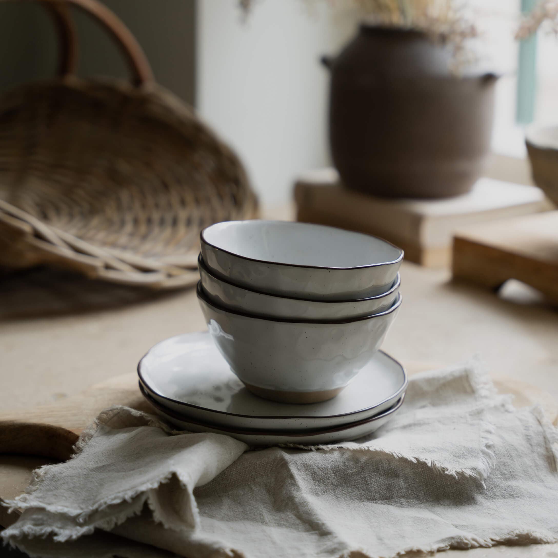 Ensemble de bols et assiettes en céramique blanche avec bord noir sur tissu en lin pour cuisine