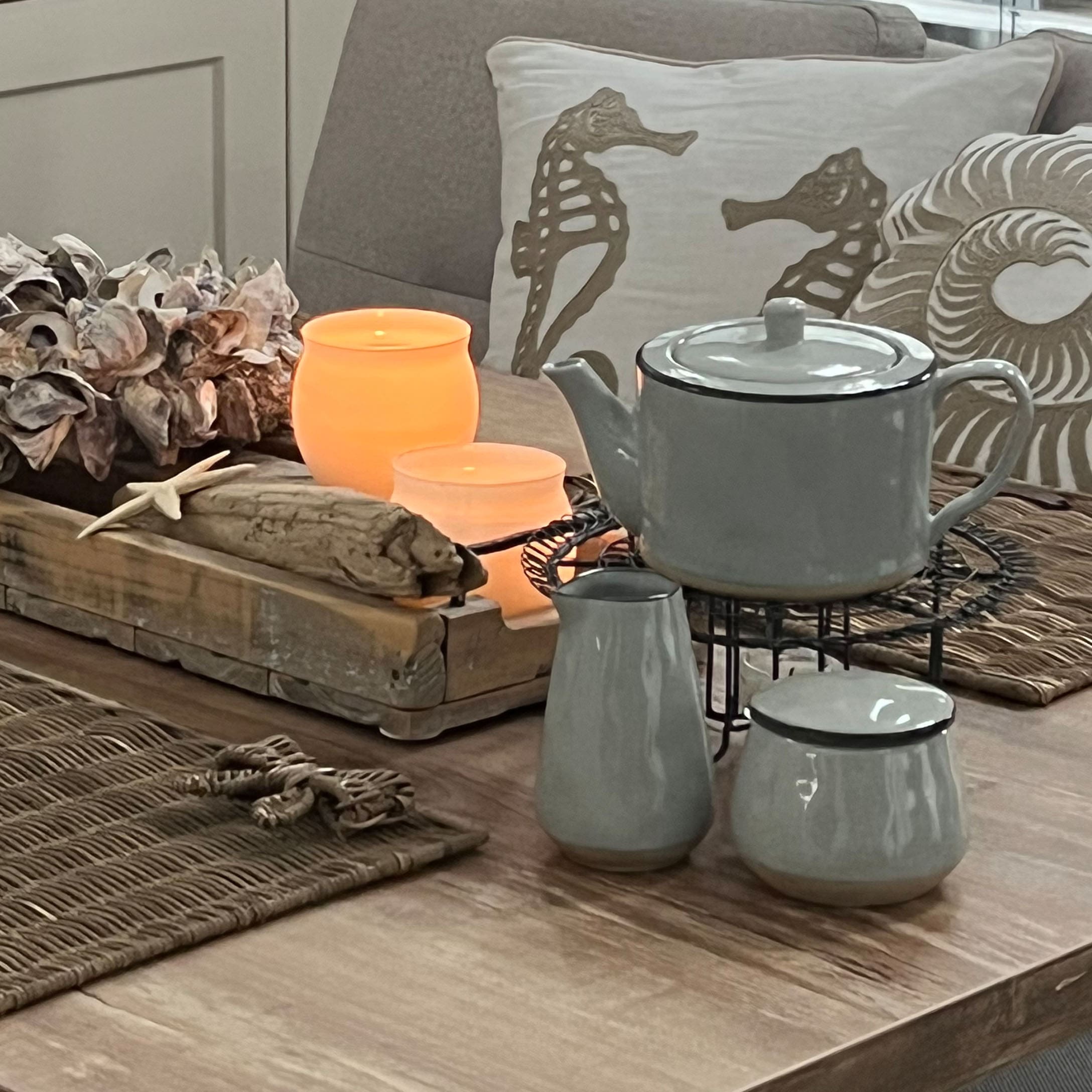 Service à thé en céramique grise sur table en bois avec décorations marines et bougies allumées