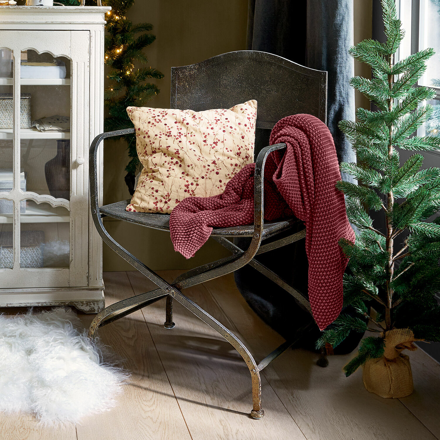 Chaise Ivilique Fauteuil en métal avec coussin à motifs rouges et plaid bordeaux dans un intérieur chaleureux avec sapin