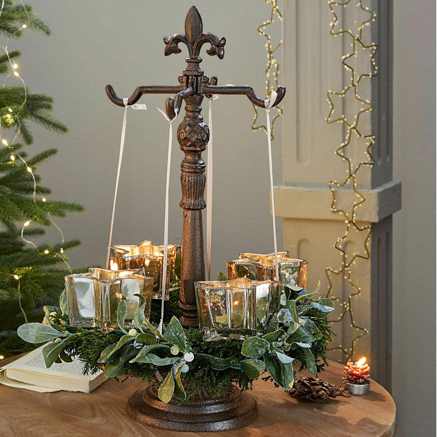 Support pour couronne Antwan Support en métal avec quatre photophores en verre et une couronne verte décorative sur une table