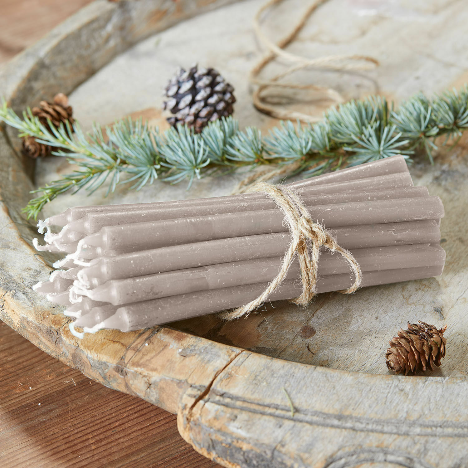 Lot de 20 bougies Lysarion Lot de bougies grises en cire liées par une corde sur un plateau en bois avec pommes de pin et branches décoratives