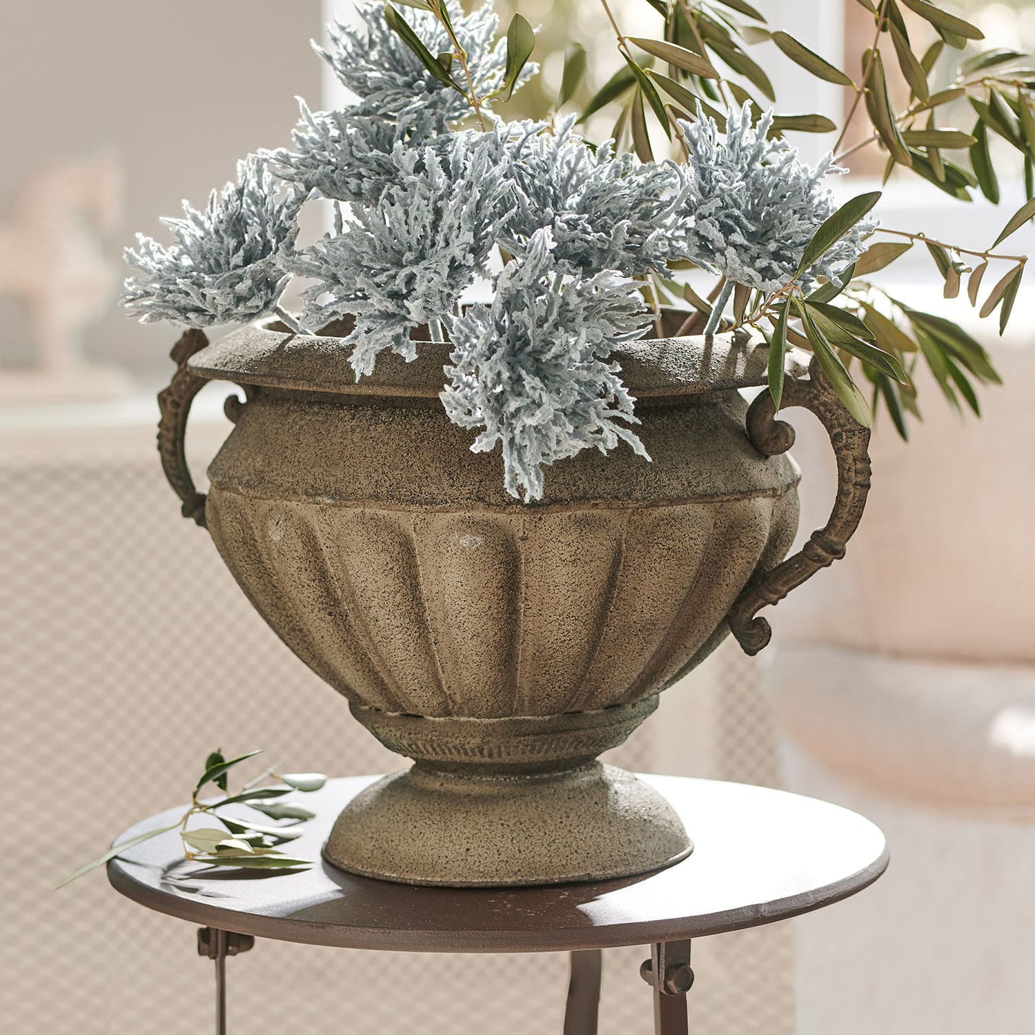 Amphore Acheville Jardinière décorative en pierre beige avec feuillage vert et gris sur une table ronde