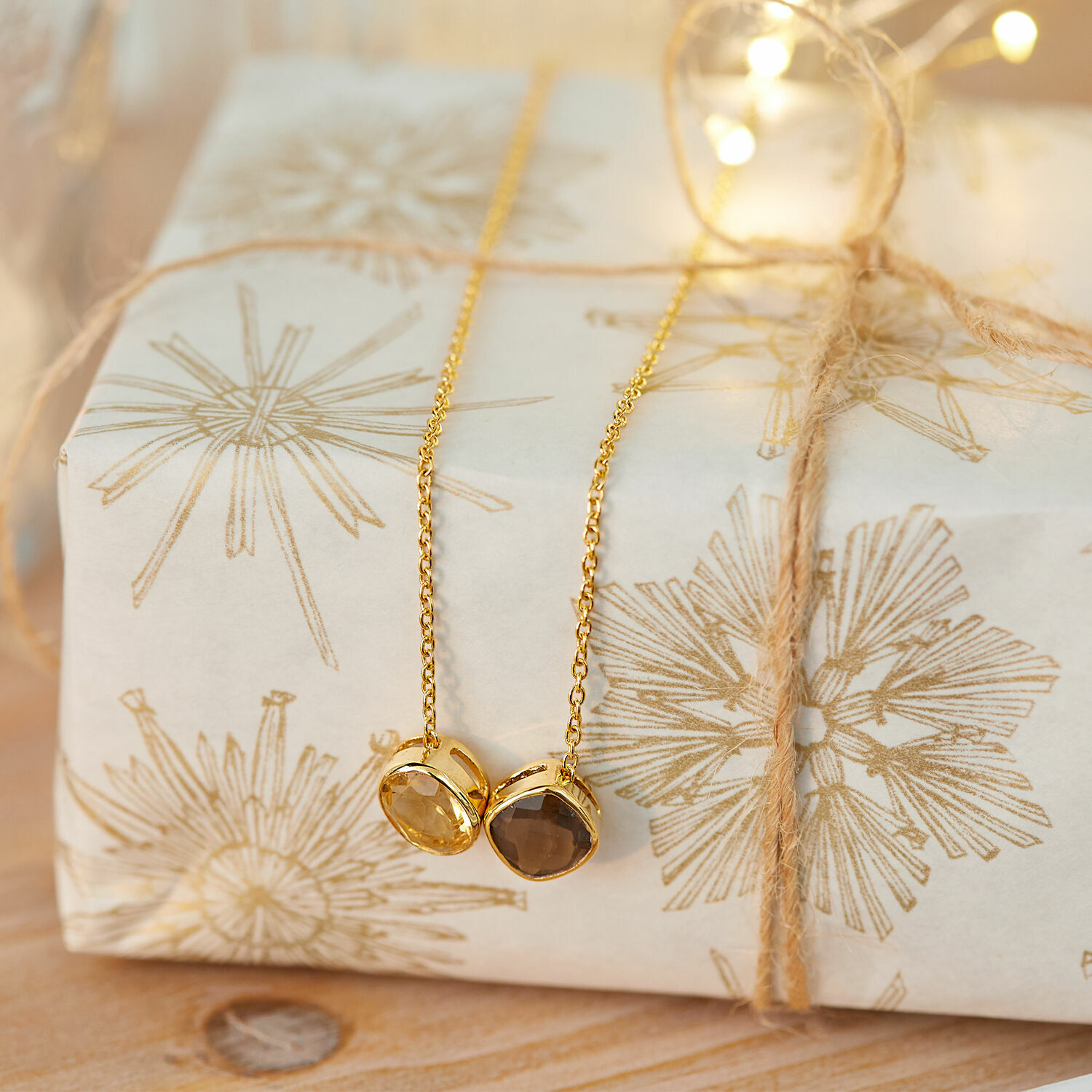 Collier Ovique Collier doré avec deux pierres sur un cadeau emballé avec papier décoratif et ficelle