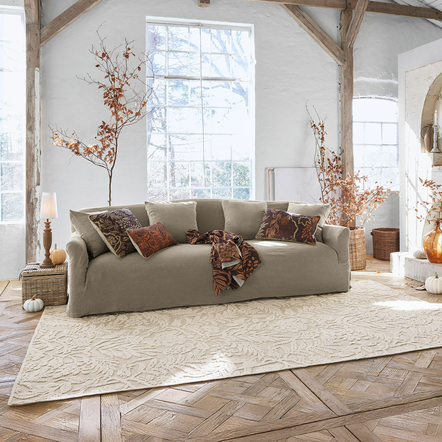 Tapis Azimra Canapé beige en tissu avec coussins décoratifs et plaid dans un salon lumineux et chaleureux