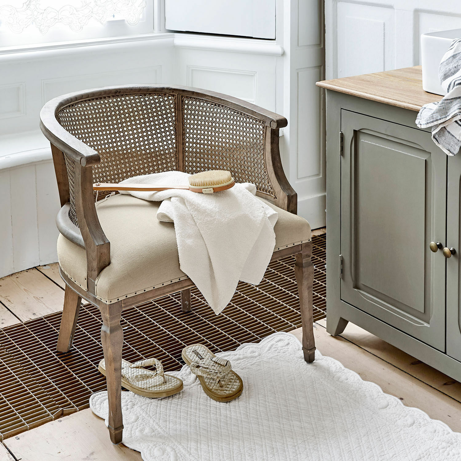 Chaise Curbigny Chaise en bois et rotin beige avec assise rembourrée et serviette blanche dans une salle de bain lumineuse