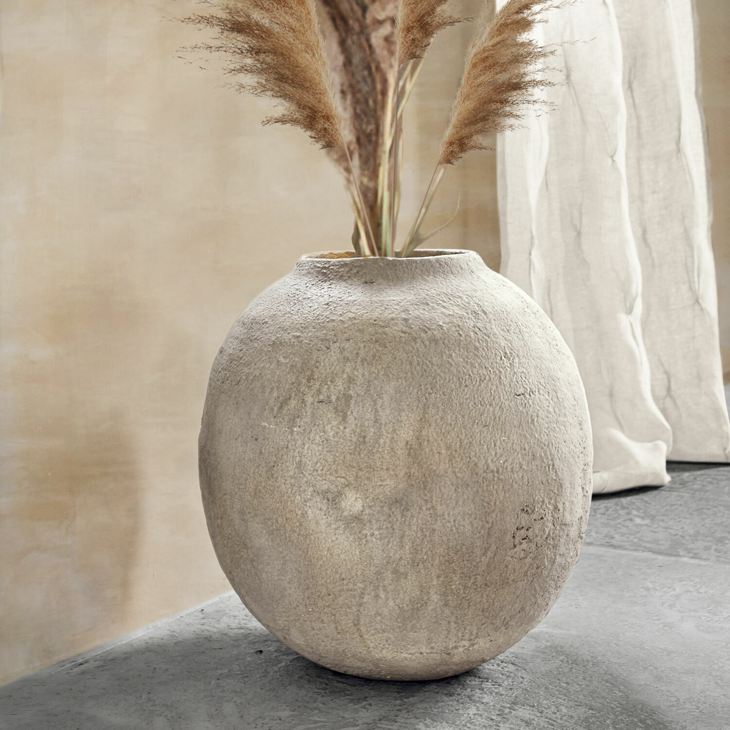 Vase Samai Vase rond en béton gris avec herbes décoratives dans un intérieur moderne et épuré