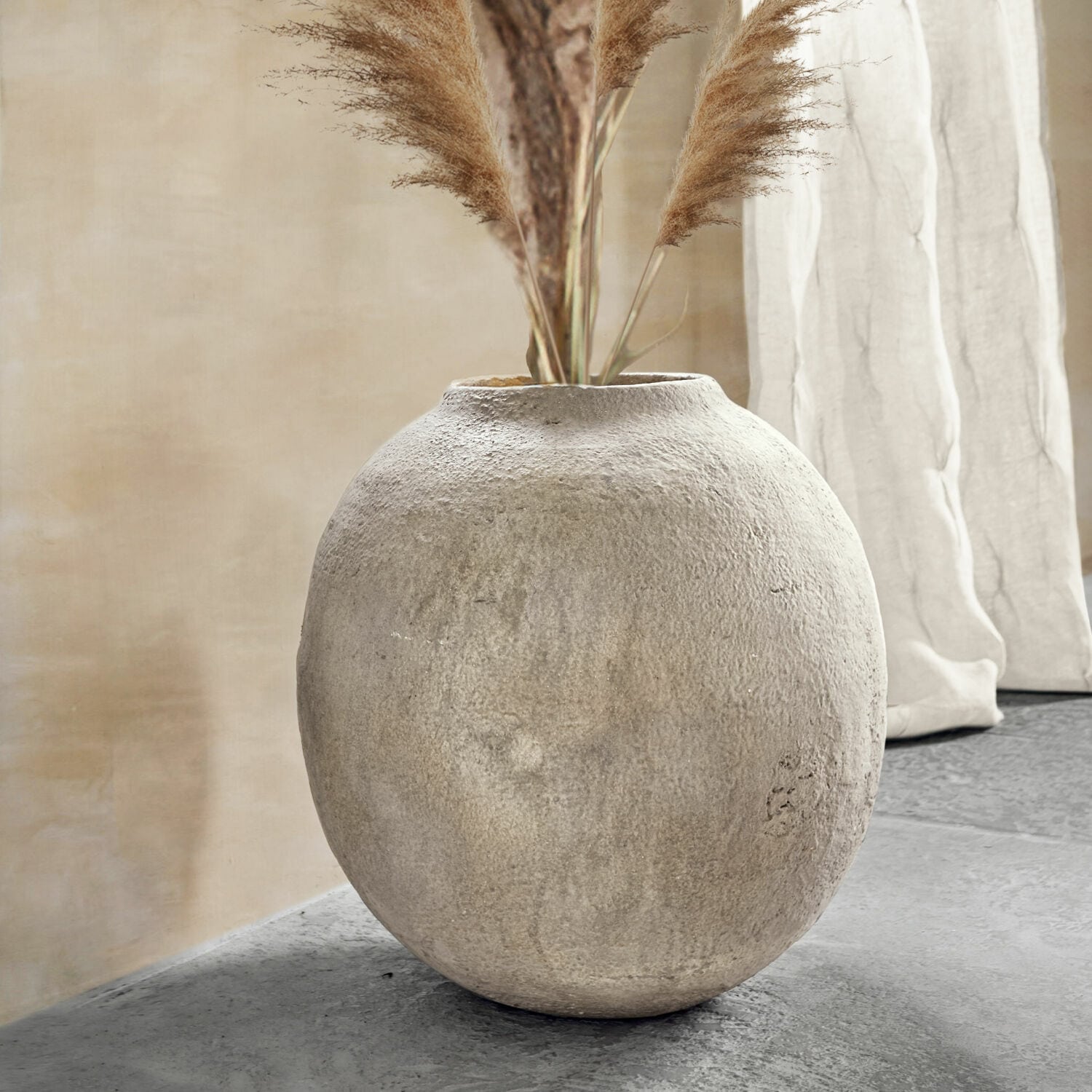 Vase Samai Vase rond en béton gris avec herbes décoratives dans un intérieur moderne et épuré