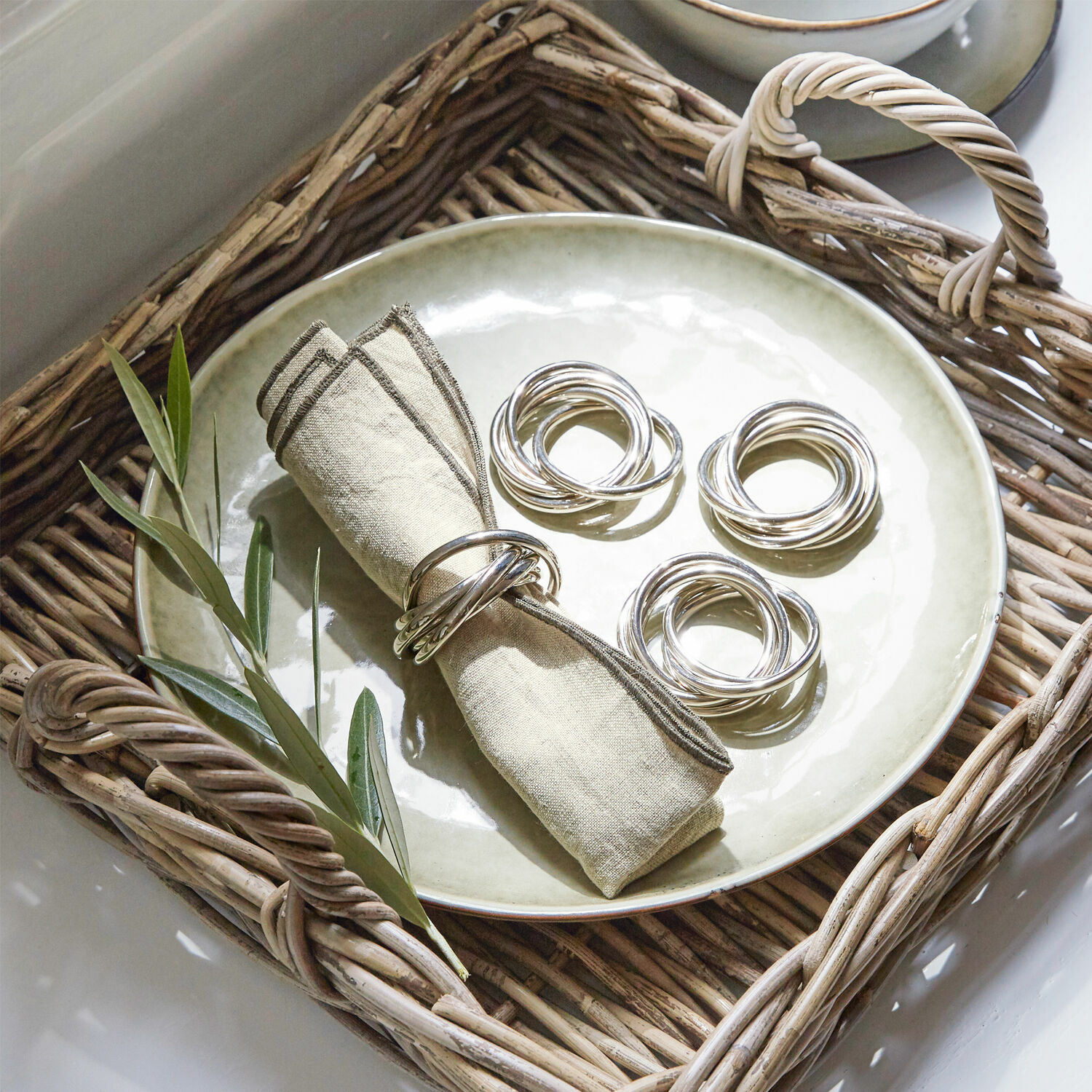Lot de 4 ronds de serviettes Limche Anneaux en argent sur une serviette en lin et une assiette dans un panier en osier pour décoration de table