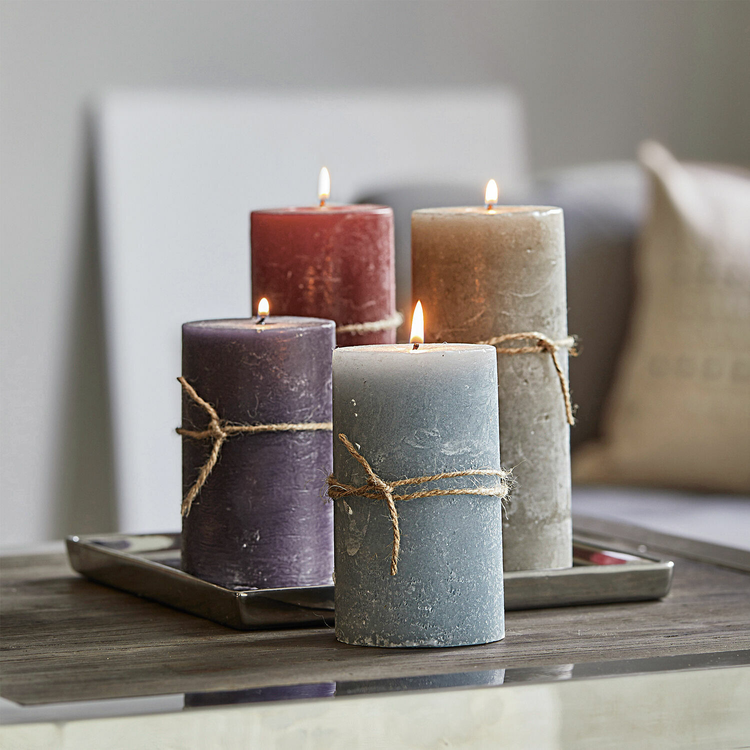 Lot de 4 bougies Berekua Ensemble de quatre bougies décoratives de différentes couleurs avec corde naturelle sur une table en bois