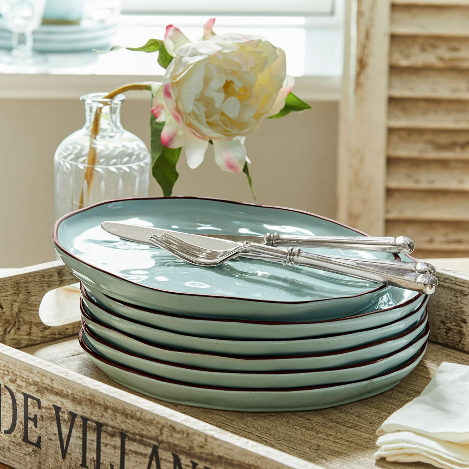 Lot de 6 assiettes Biarré Ensemble de six assiettes en céramique vert menthe avec bord brun posées sur un plateau en bois
