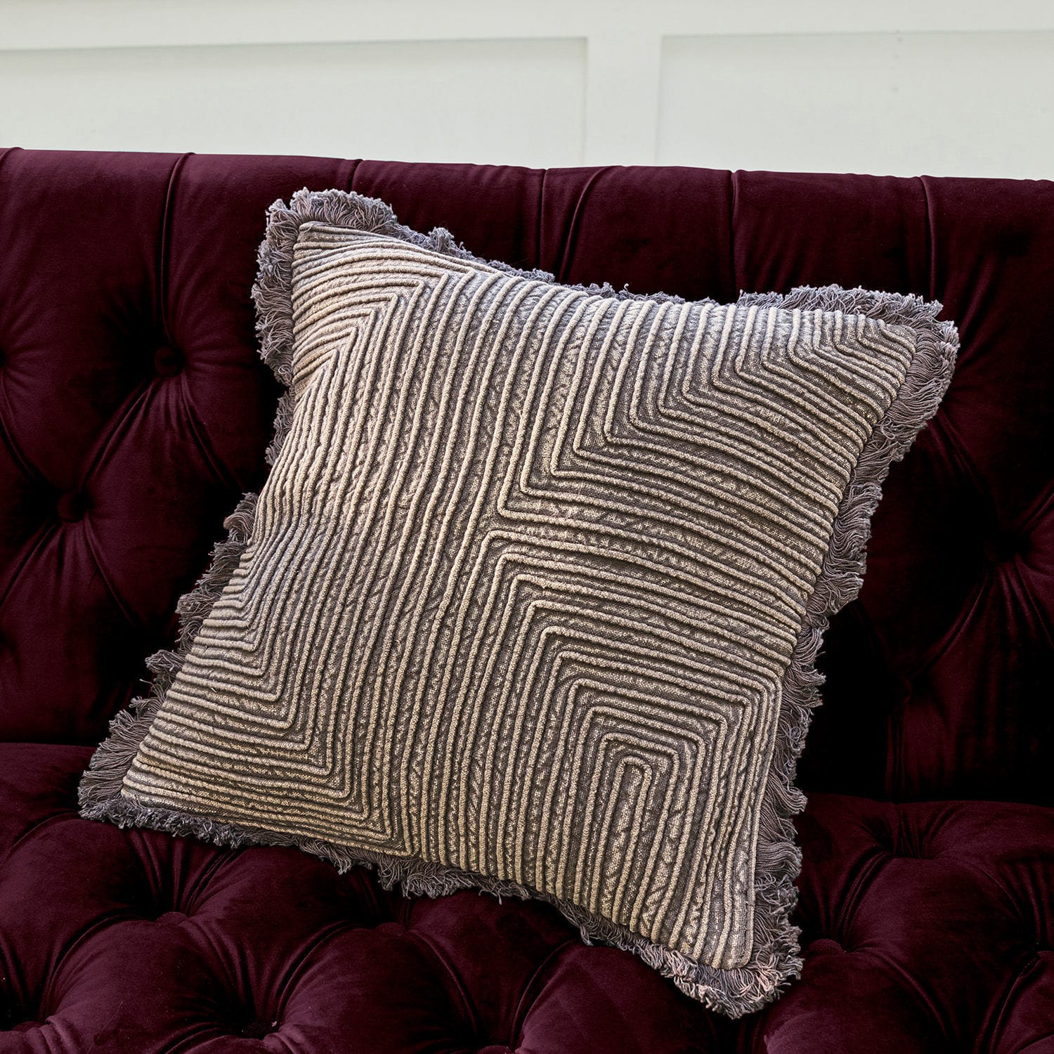Housse de coussin Cairon Coussin décoratif gris avec motif géométrique et franges sur un canapé en velours bordeaux