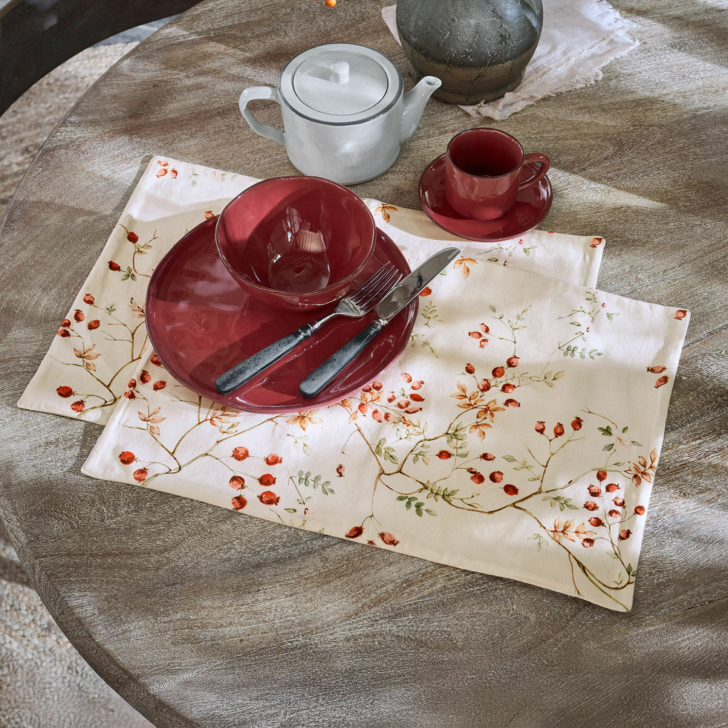 Lot de 2 sets de table Mauriac Service en céramique rouge sur nappe en lin à motif fruits sur table en bois rustique