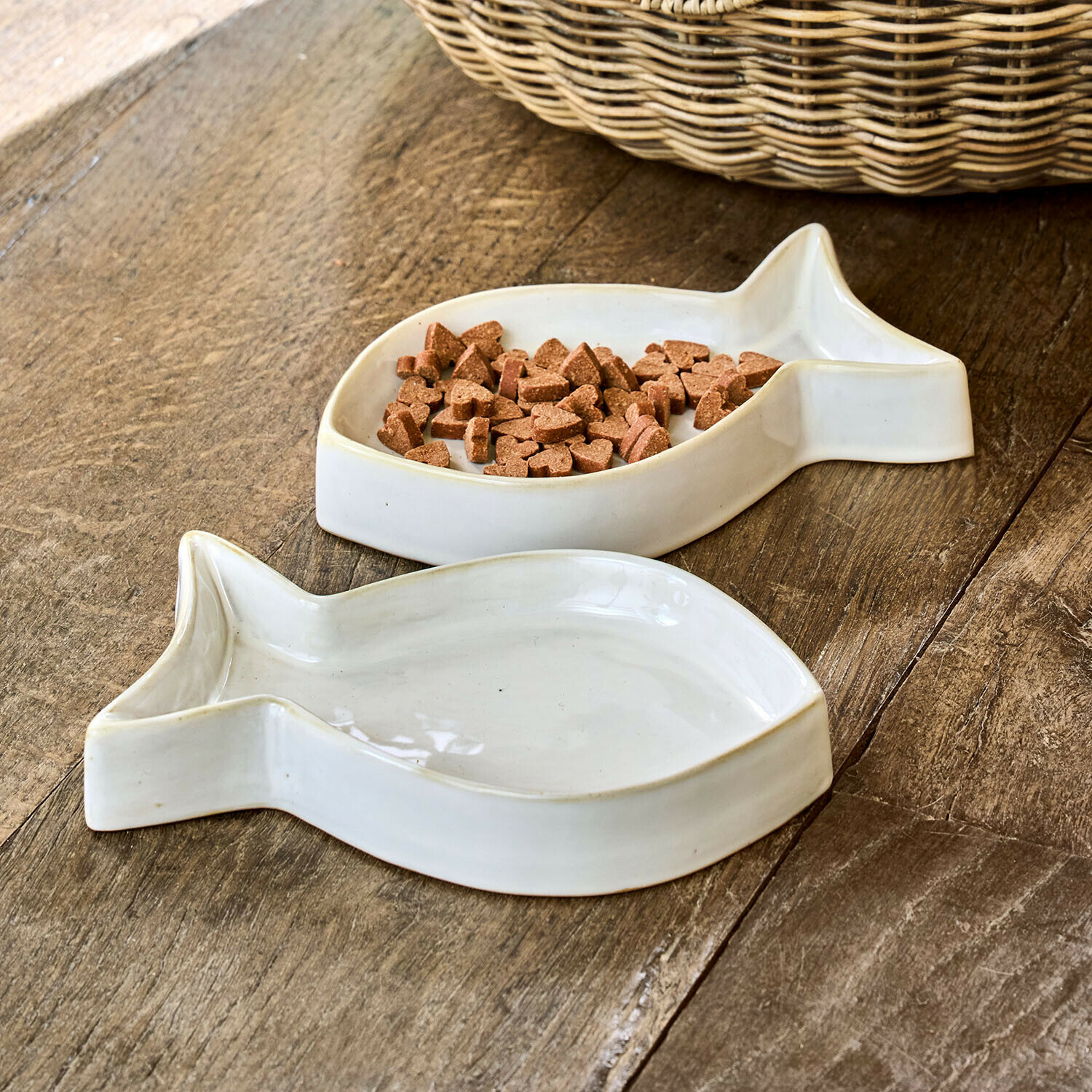 Lot de 2 gamelles Felluna Deux gamelles en céramique blanche en forme de poisson pour nourriture animale sur table en bois