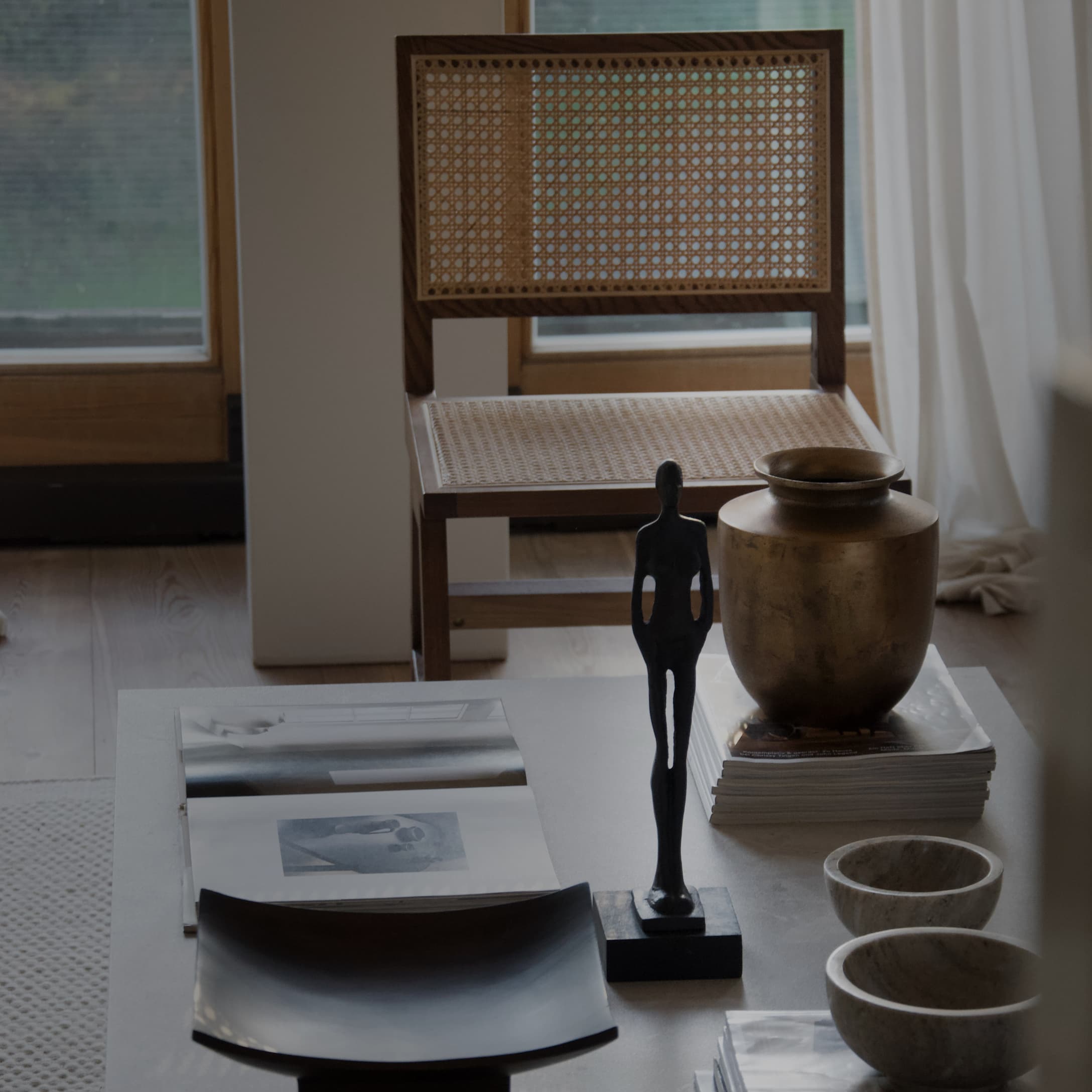 Table décorative avec une figurine noire, un vase doré et des bols en céramique dans un intérieur lumineux
