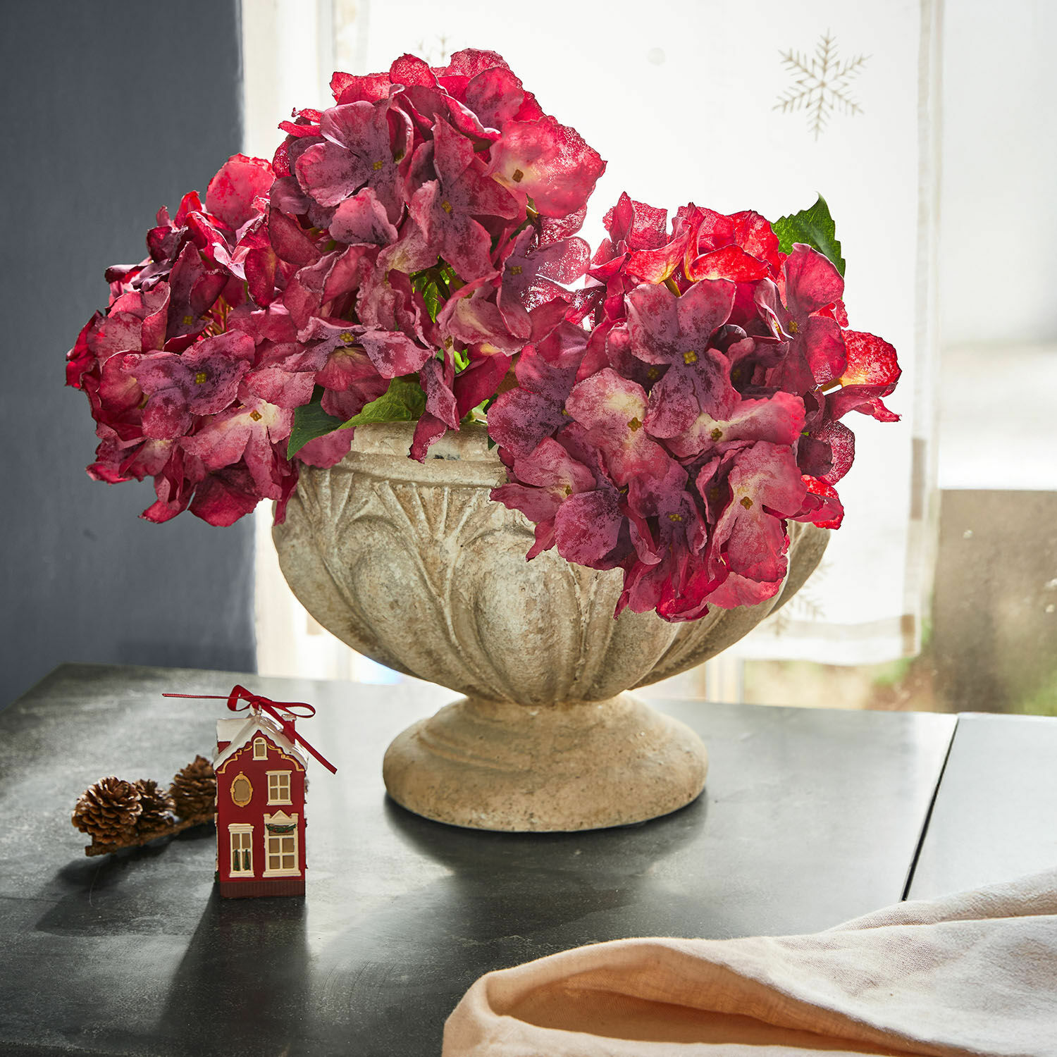 Amphore Orlida Coupe en pierre décorative avec fleurs rouges sur table, décoration intérieure et saisonnière élégante