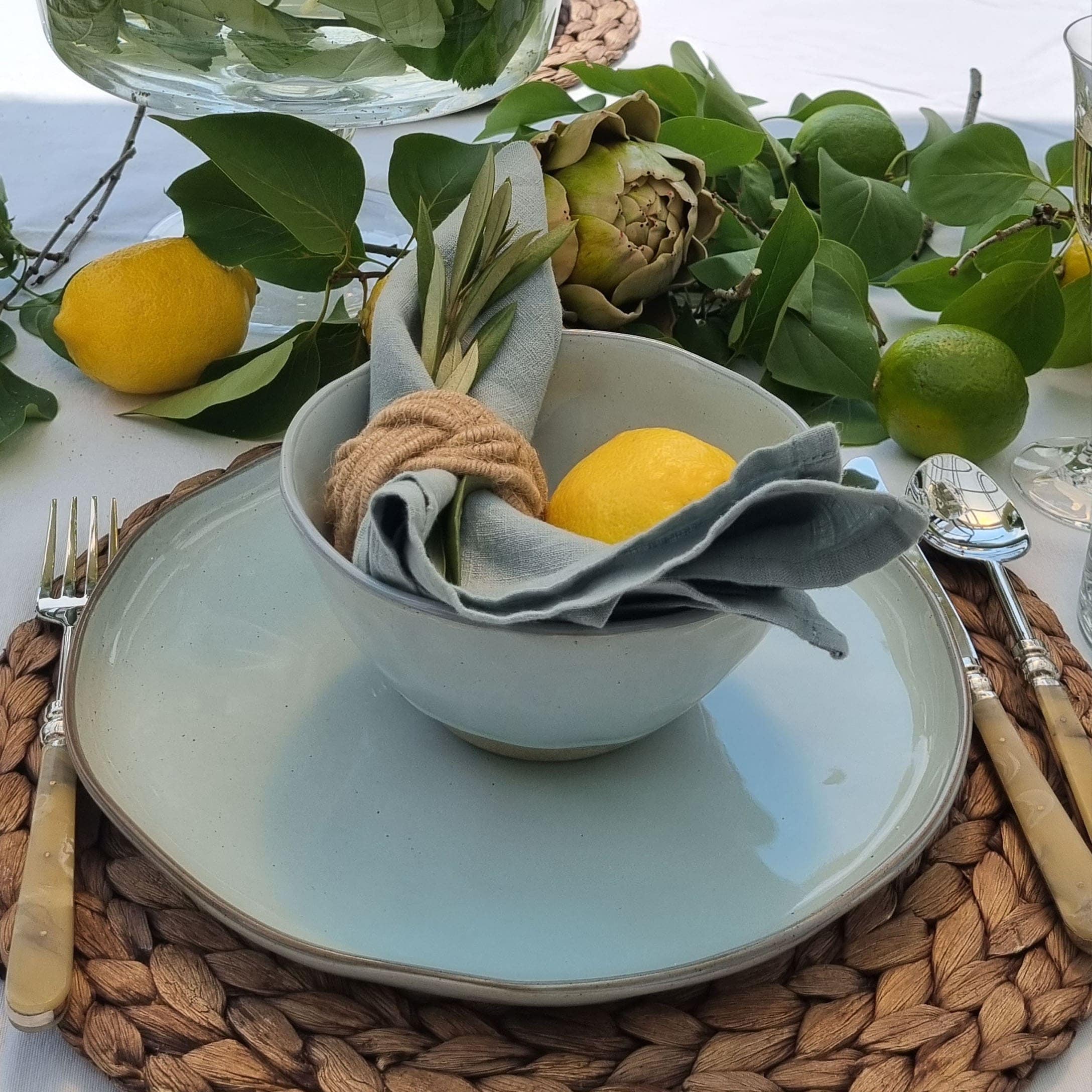 Service de table avec bol et assiette en céramique claire sur napperon tressé avec décoration citron
