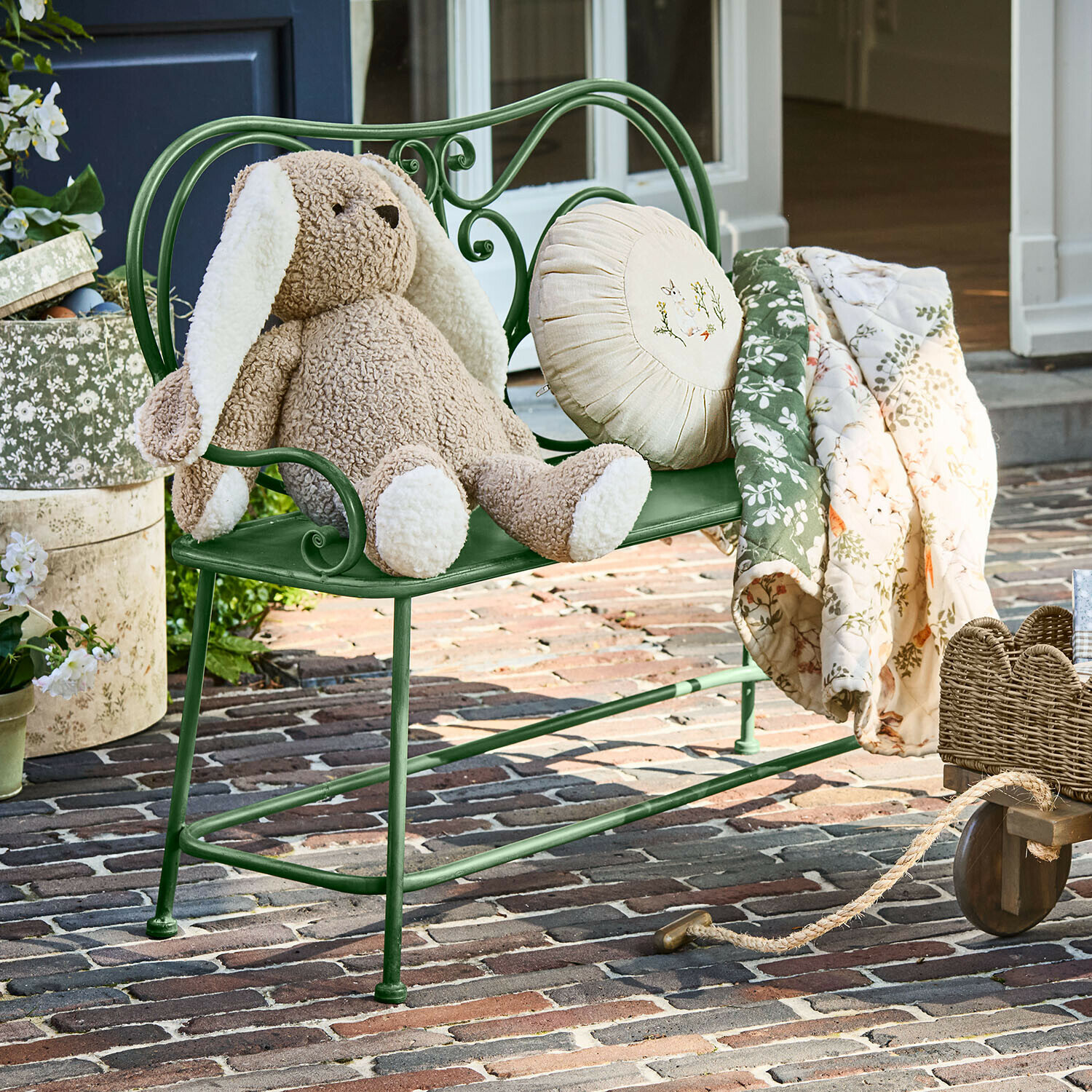 Banc pour enfant Fernwick Banc en métal vert avec peluche lapin beige et couverture fleurie sur patio en briques