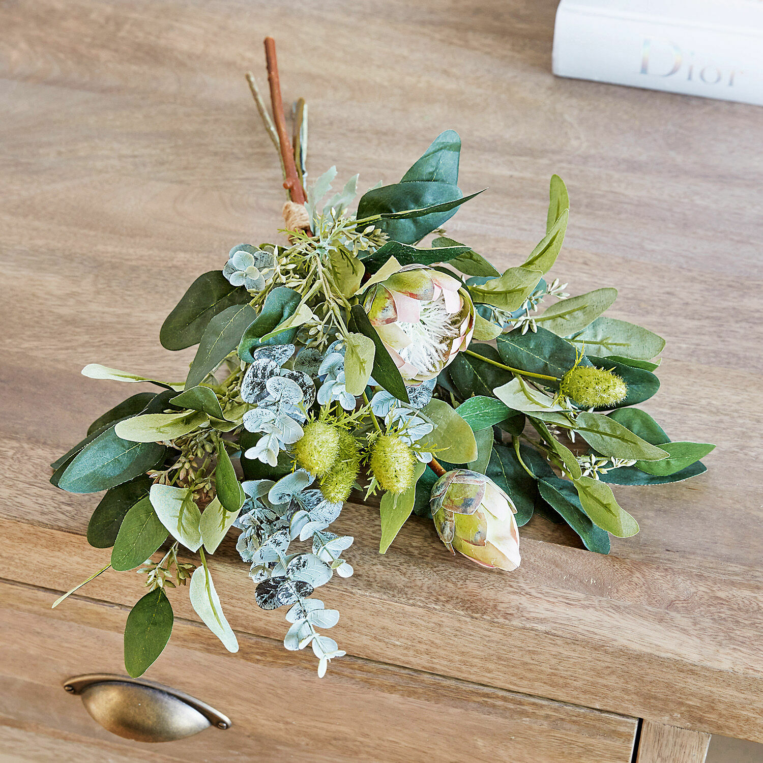 Bouquet de feuilles et fleurs artificielles vertes sur une surface en bois pour décoration intérieure