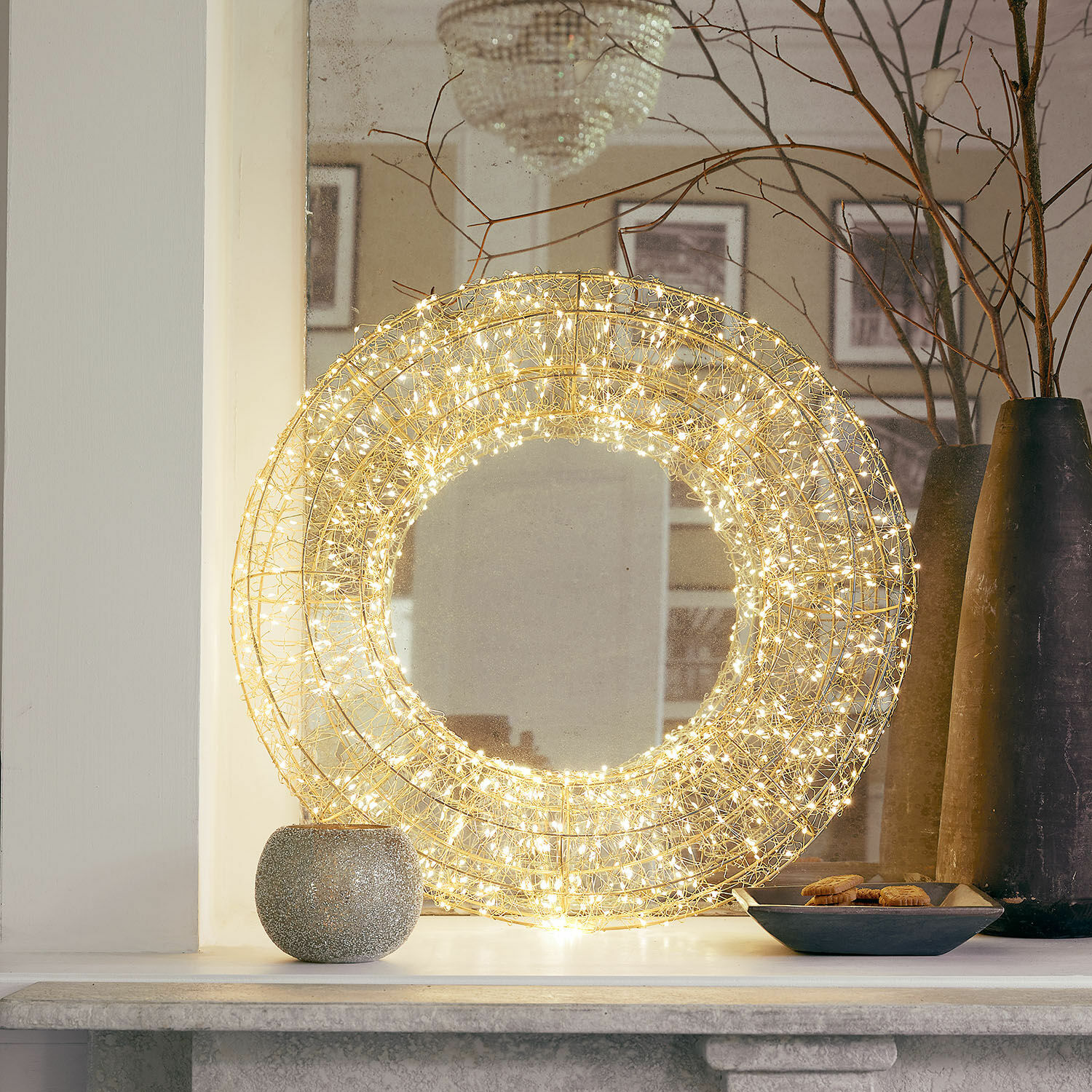 Couronne à LED Veralisse Décoration lumineuse ronde en fil métallique doré avec LED chaudes posée sur une cheminée