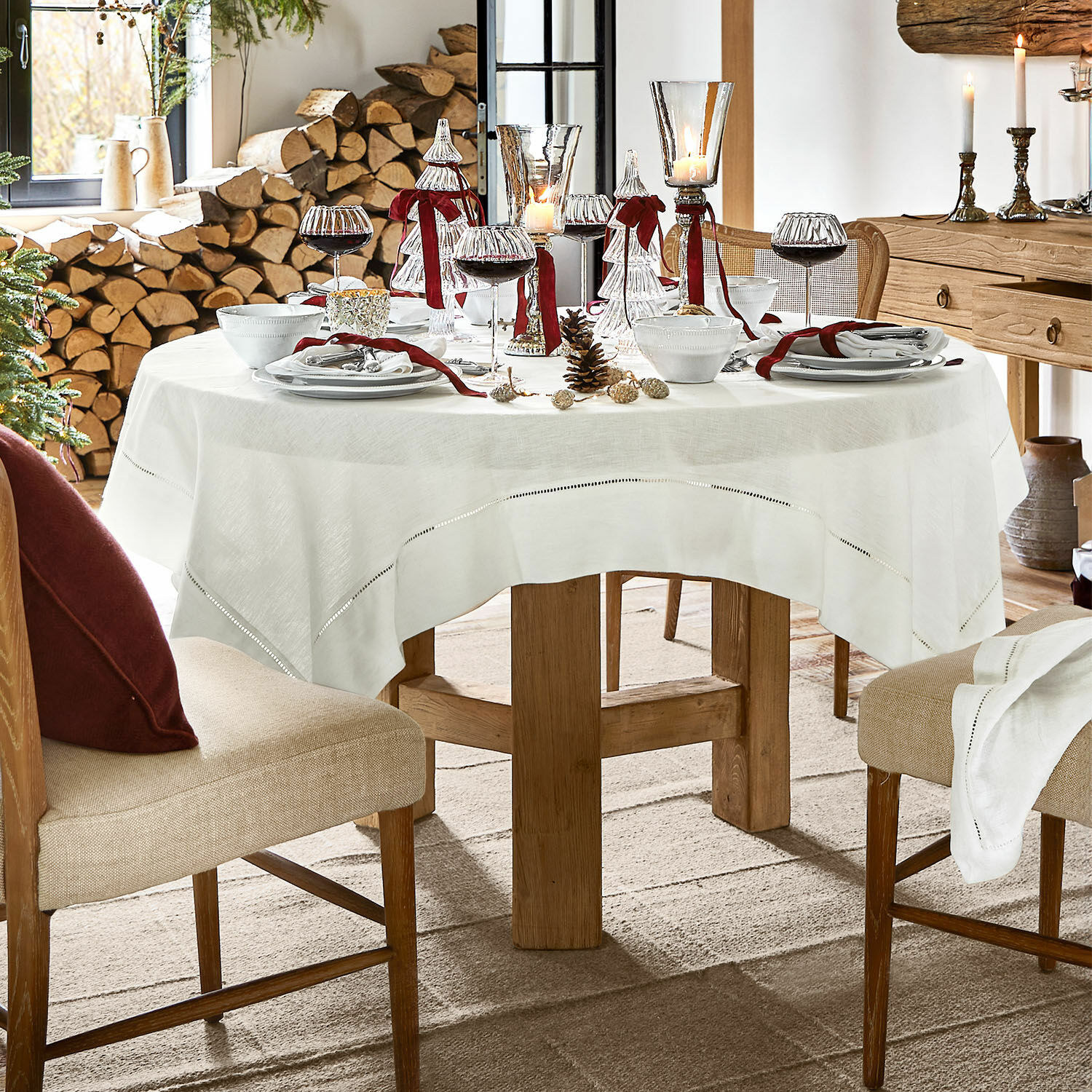 Nappe Covent Garden Table ronde avec nappe en lin blanc et décorations de Noël dans un intérieur rustique en bois
