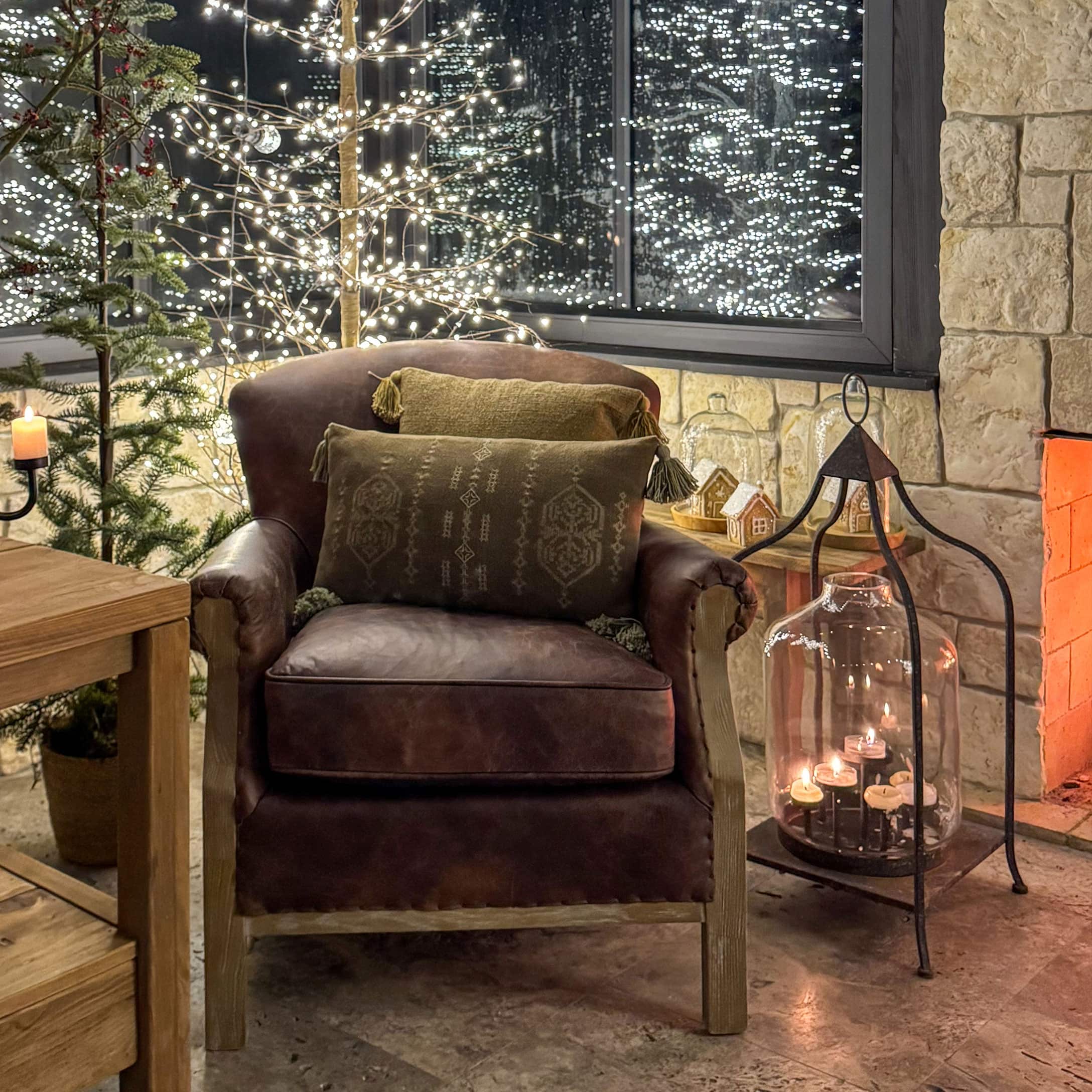 Fauteuil en cuir marron avec coussins dans un intérieur chaleureux décoré pour Noël avec bougies
