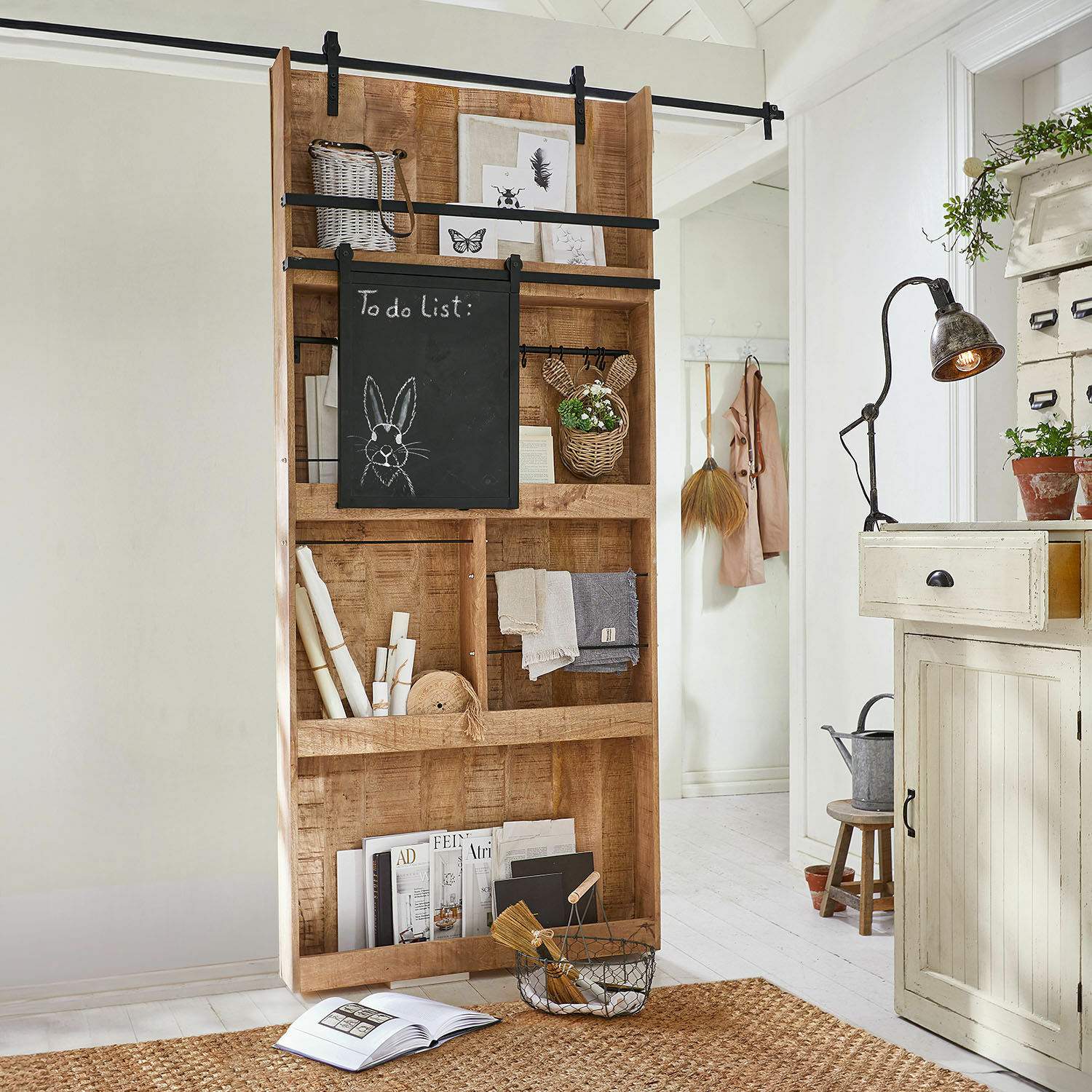 Porte coulissante Vulmont Étagère en bois avec tableau noir et décorations dans un intérieur clair avec tapis en jute